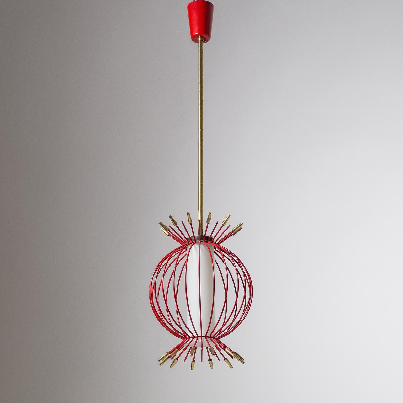Rare and very unique midcentury pendant with a slender satin glass diffuser surrounded by a red lacquered cage with brass details. Fine original condition with patina on the brass and minor loss of paint. One brass E14 socket with new wiring. Height