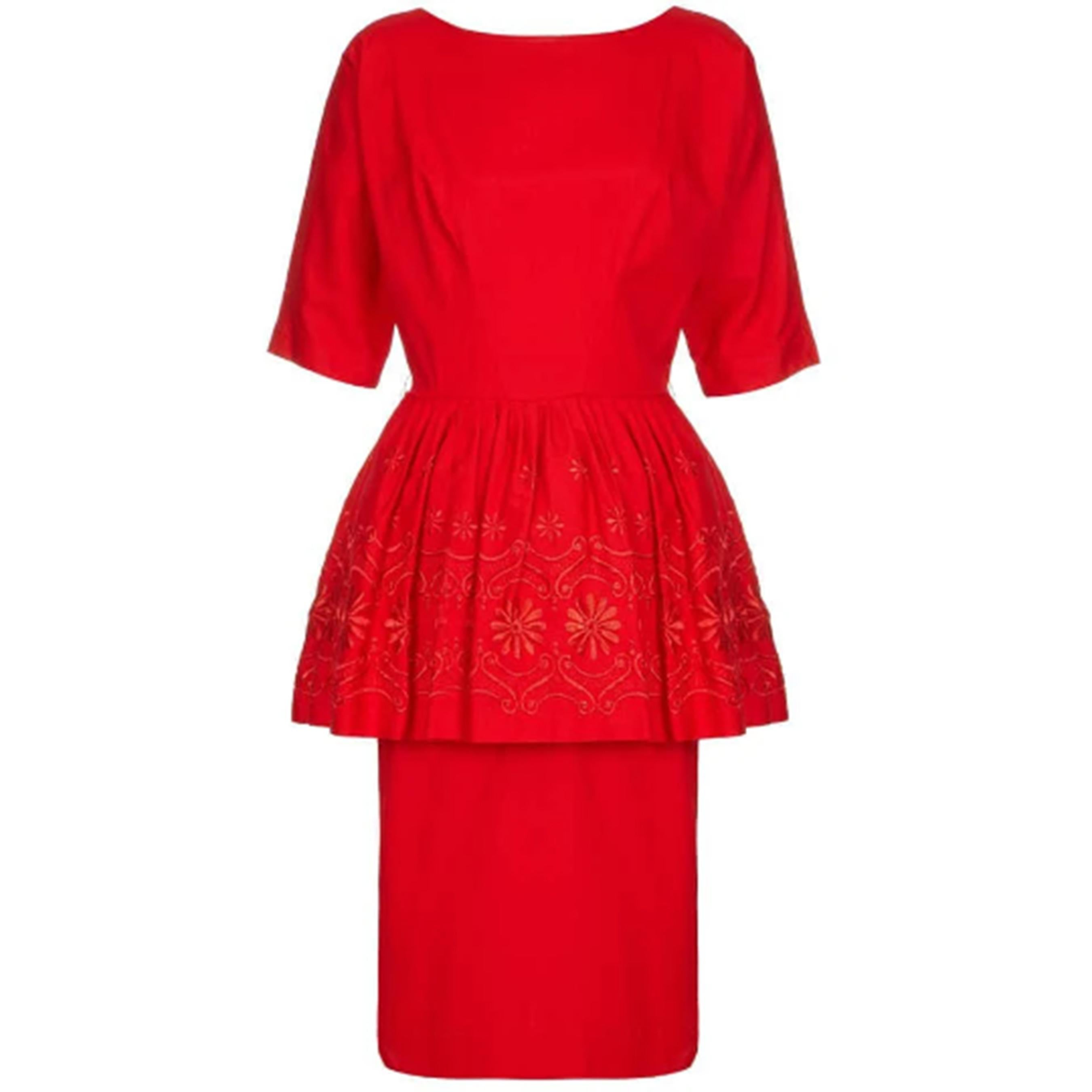 Rotes Baumwollkleid aus den 1950er oder frühen 1960er Jahren mit Blumenstickerei und plissiertem Schößchen. Das Kleid hat außerdem ellenbogenlange Ärmel, ein tailliertes Oberteil und einen Unterrock und wird hinten mit einem Reißverschluss