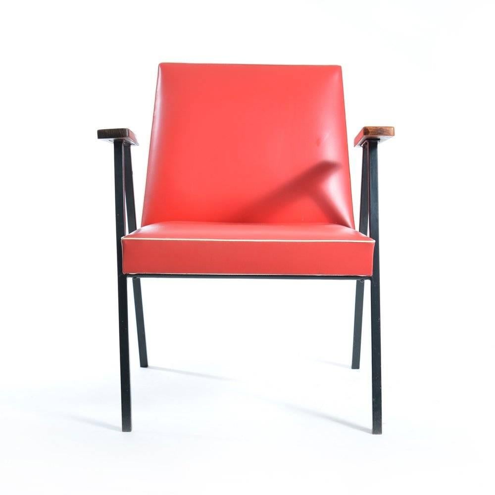 These 1950s armchairs are simple, yet very original. Their look elegant, yet sharp. The black metal legs hold the red leatherette seat with a white hem around it. The back side is edged with round metal studs. The seat is in very good condition. The