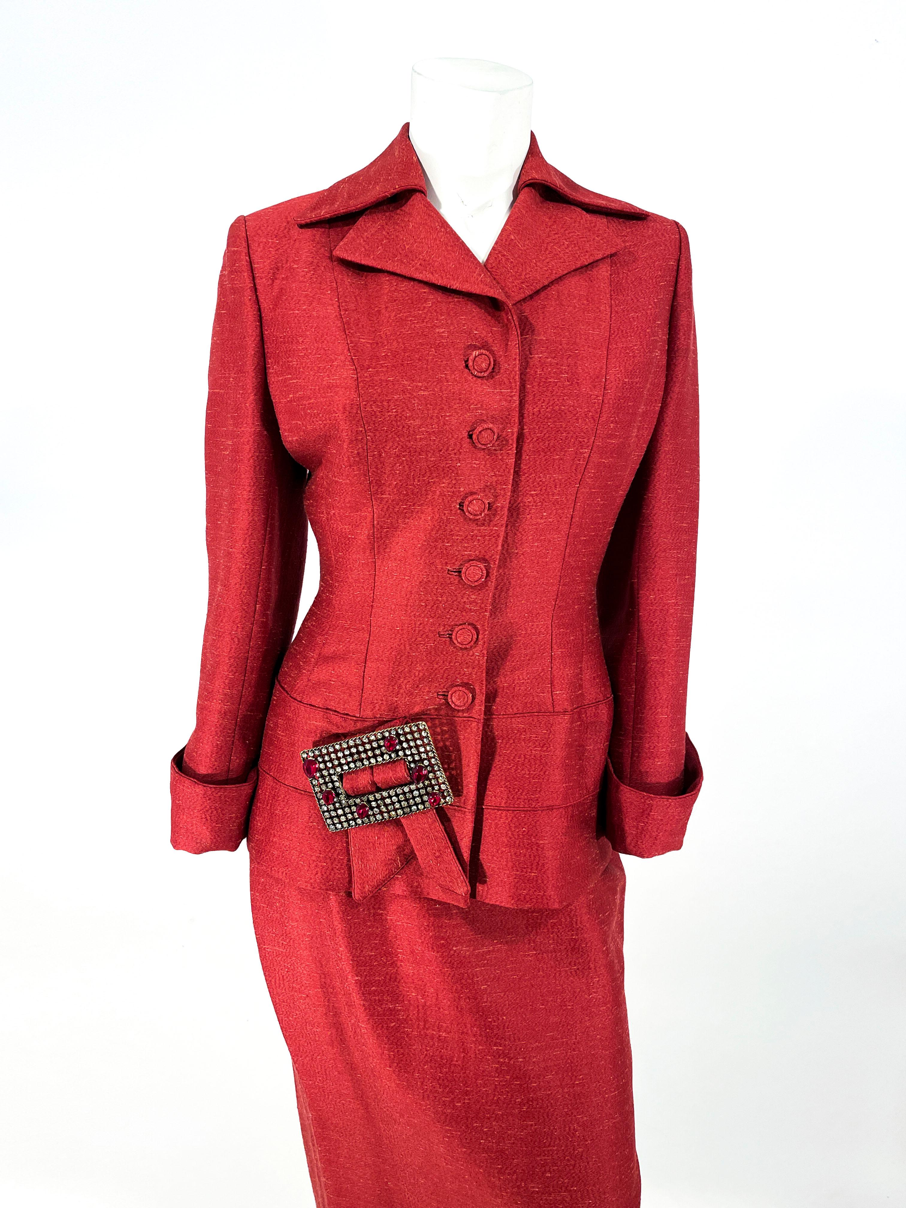 1950s Red Lilli Ann wool and silk blend jacket and skirt suit. The suit jacket features a sharp collar, notch lapel, designer covered buttons, in-set button holes, fitted and tailored wasp waist, and an enlarged clear and red rhinestone buckle