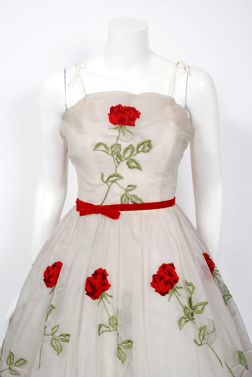 This is perhaps the most darling and flattering 1950's floral party dress I have ever seen. Fashioned from red-rose floral garden embroidered ivory silk-organza, you can tell the fabric is of the highest quality. The bodice has stunning thin bow-tie