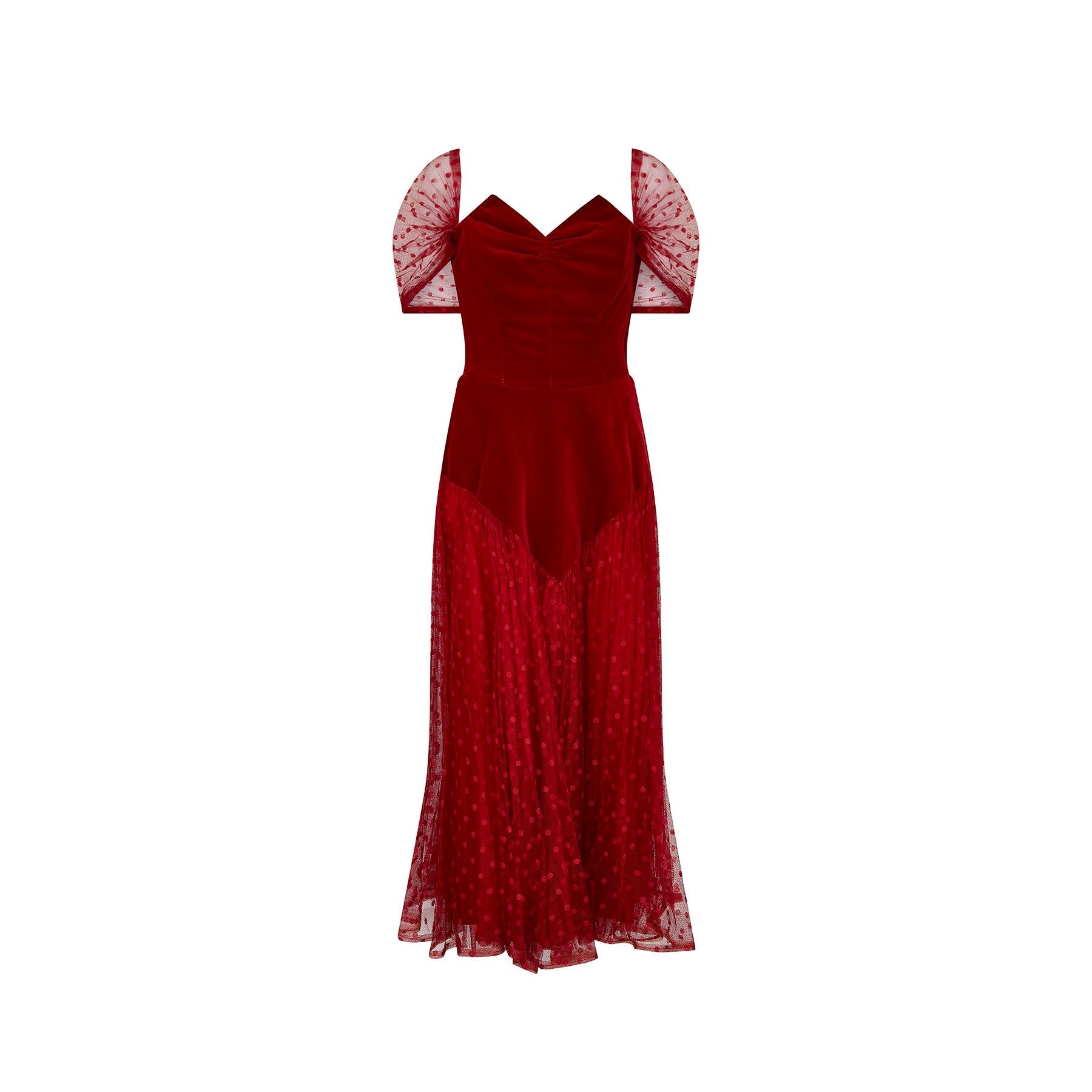 An exceptional red velvet and tulle evening dress in a classic 1950s silhouette. The main bodice is made from a deep crimson red velvet, with a gathered bust which has internal boning to add structure. The dress fastens down the side with the