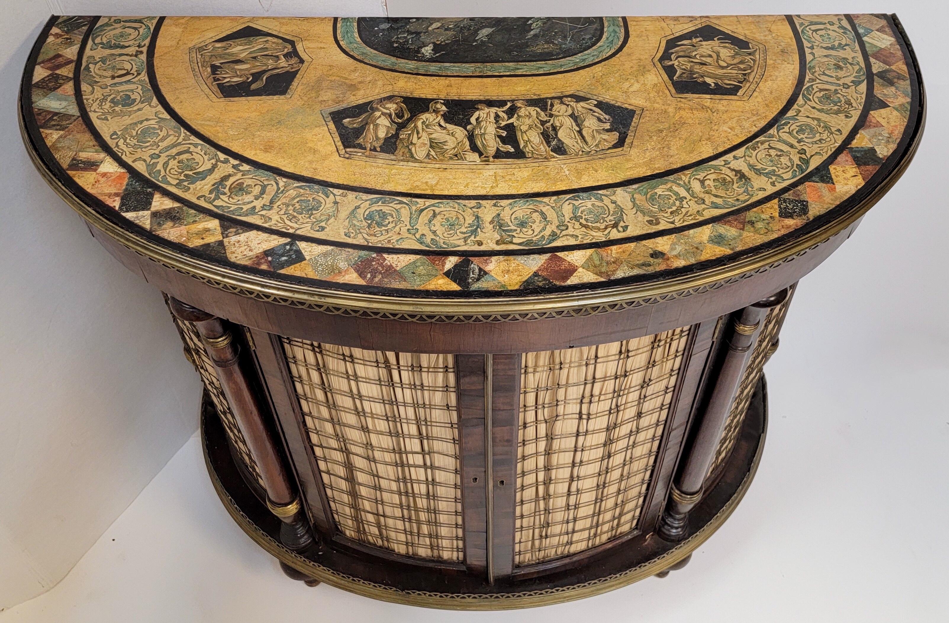 This is a 1940s/50s Regency Pietra Dura style painted flame mahogany demilune cabinet. It has a nice brass gallery and single interior shelf. The beautiful painted top is in the manner of Pietra Dura. It is unmarked.