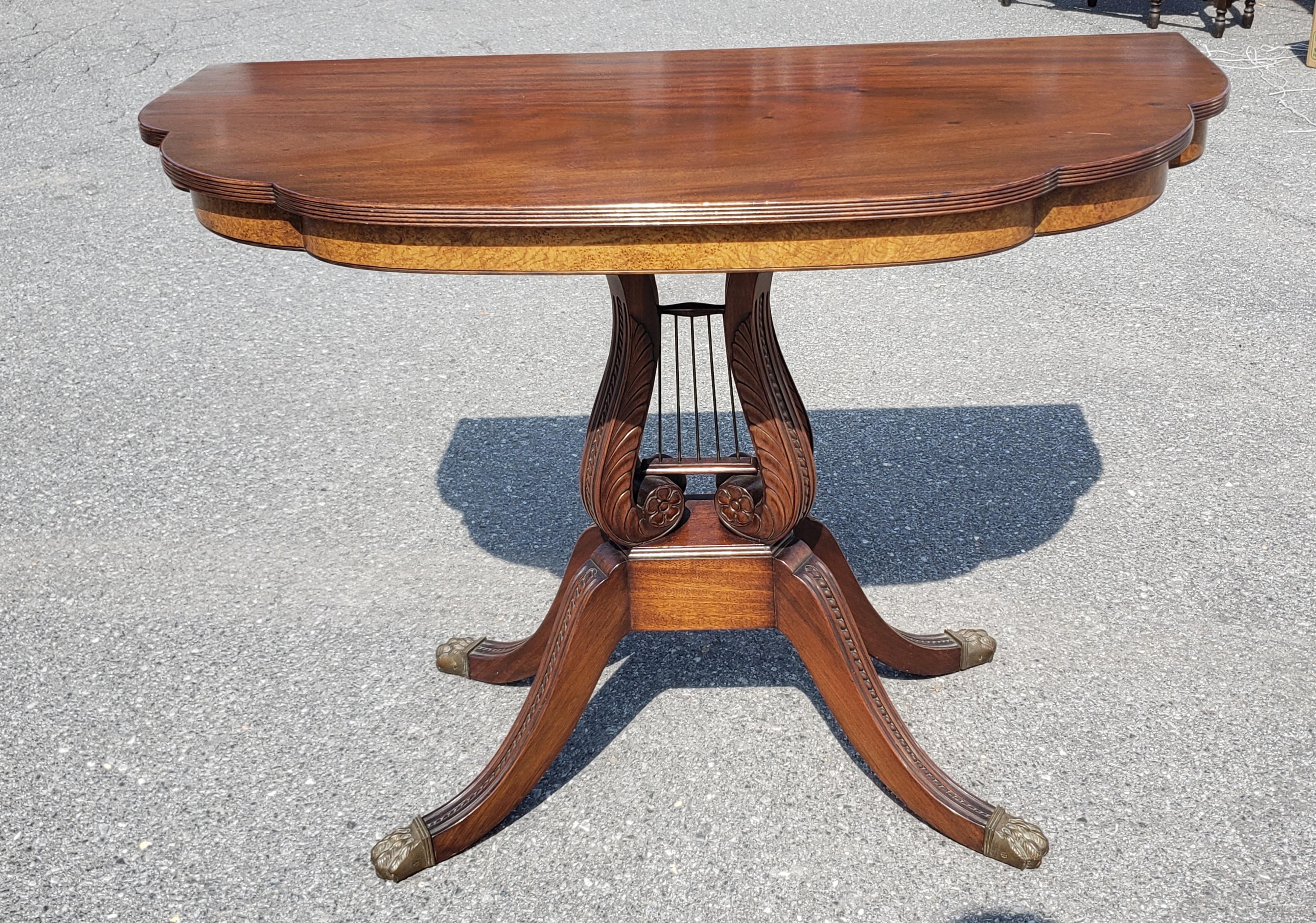 A 1950s Regency Style Mahogany Quadpod Lyre Pedestal Console Table with brass cap paw feet and walnut burl skirt.
Measures 42