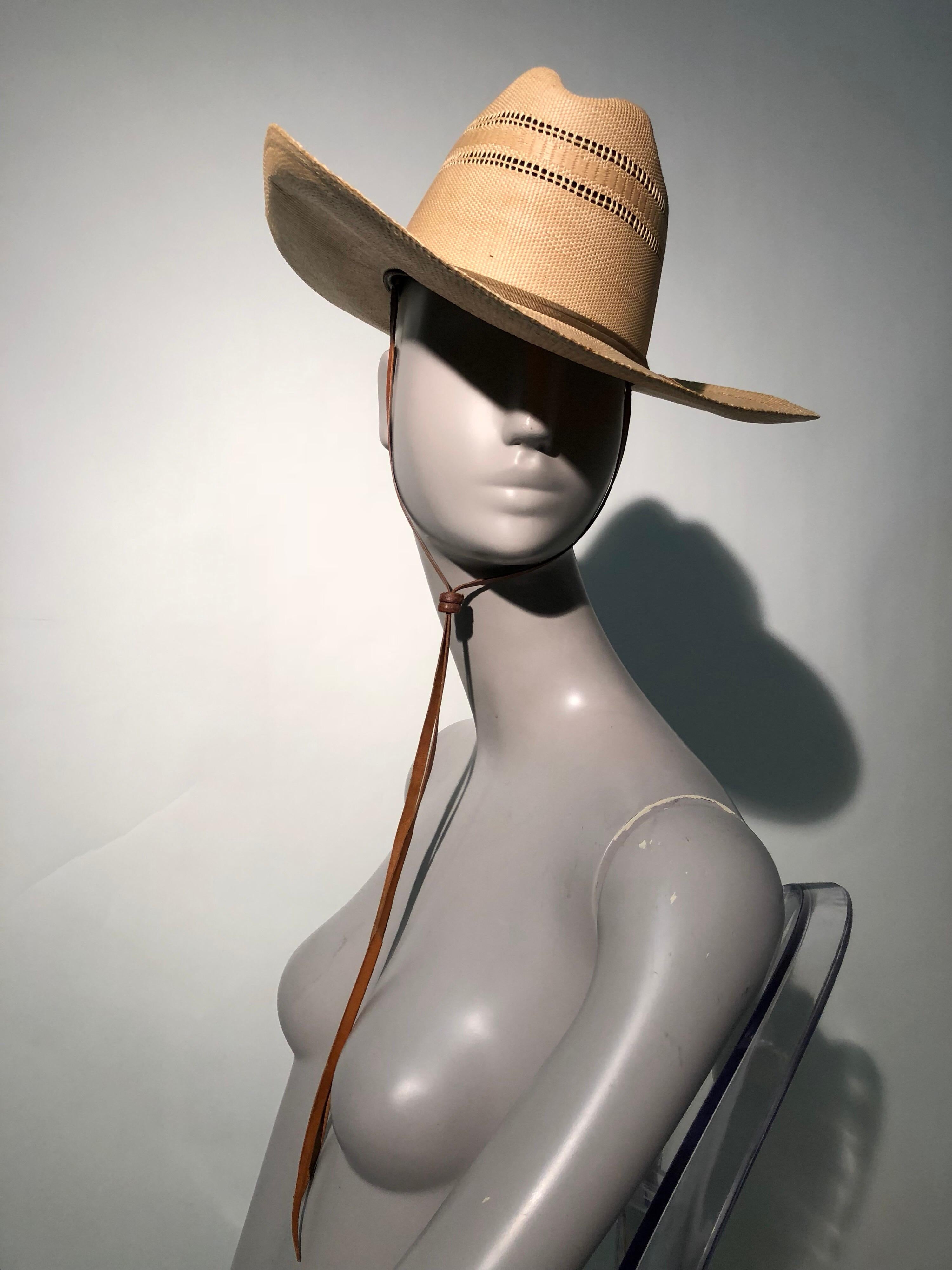 A wonderful 1950s Resistol woven straw cowboy or western hat. Wide, stiffly structured straw brim won't sag or blow in the wind and the crown features woven-in ventilation. A leather chin strap is secured with 2 heavy leather toggle-like clasp