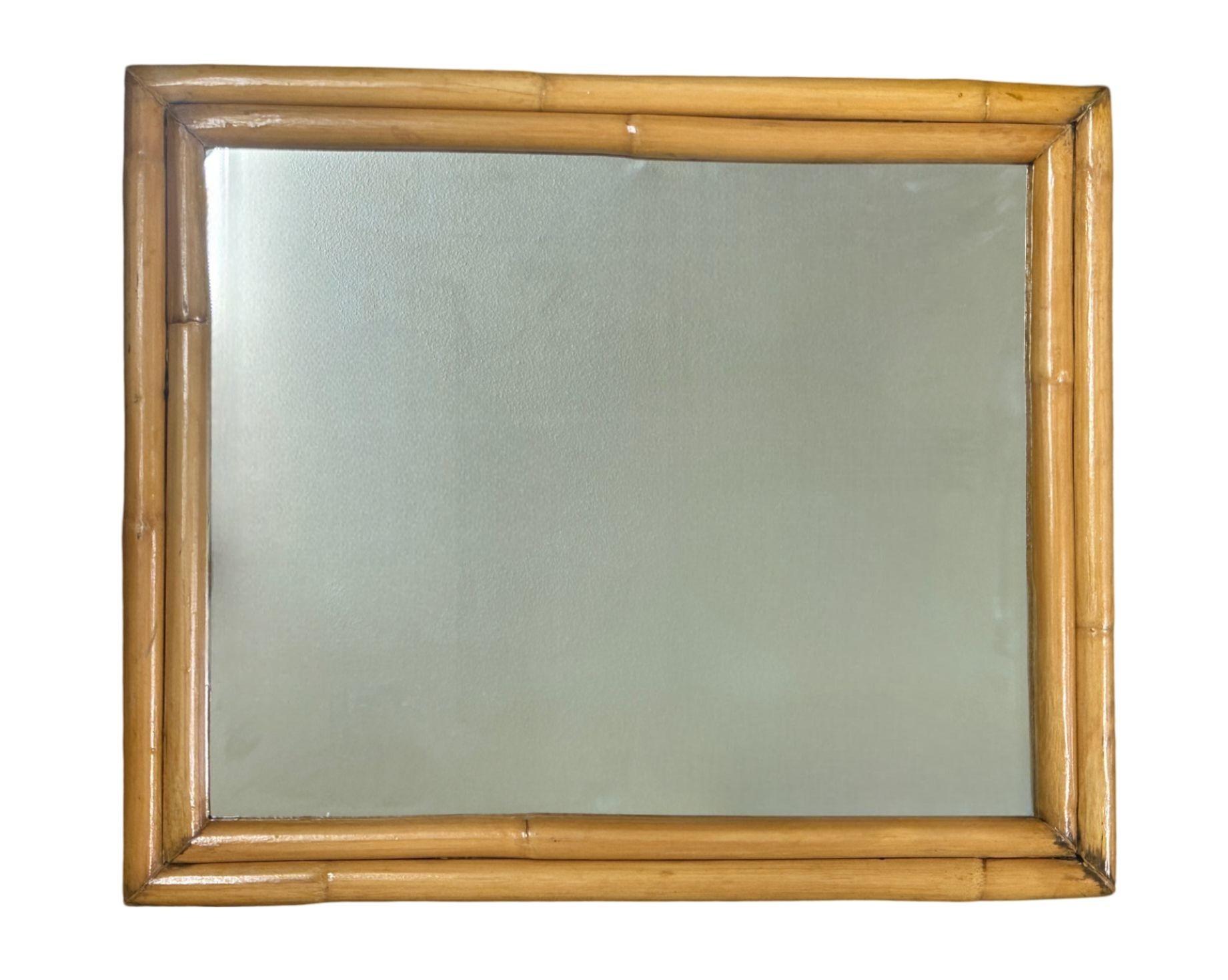This beautifully restored Paul Frankl-inspired 19-inch-tall rectangular mirror, framed in a beautifully crafted double-strand rattan design. The outer frame's natural texture is complemented by a delicate inner rattan border, creating a layered,