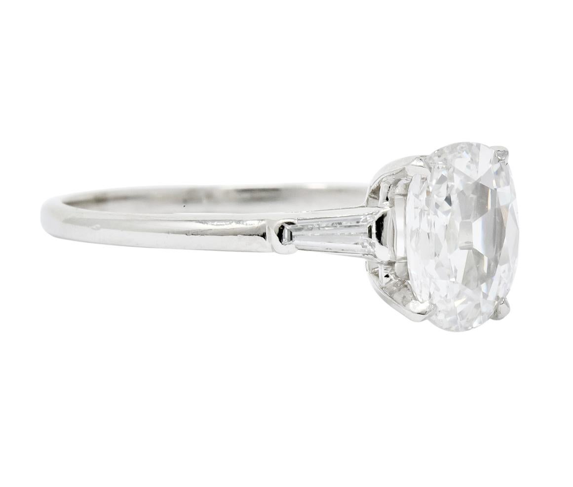 Centering an ovalish pair cut diamond weighing approximately .97 carat total, F color and VS2 clarity, prong set in a platinum cathedral mounting

Accented by two tapered baguette diamonds weighing approximately 0.16 carat total, F-G color and VS