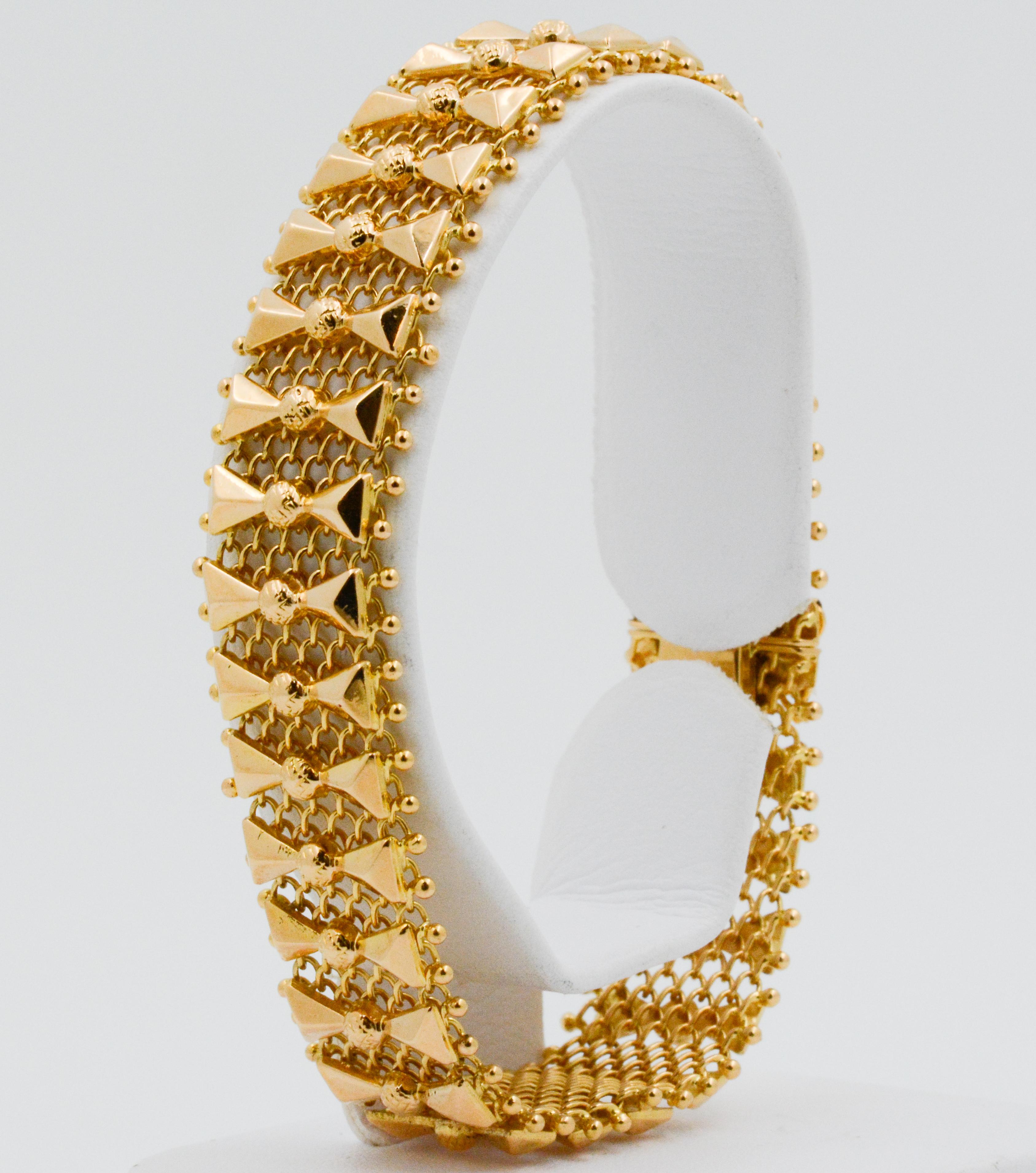 From the 1950s this retro 18k yellow gold bracelet that features two polished pyramid design with dot centers laying vertically on top of chainmail. The dot centers have a weave design that resemble a bow or the Golden Snitch from Harry Potter. The