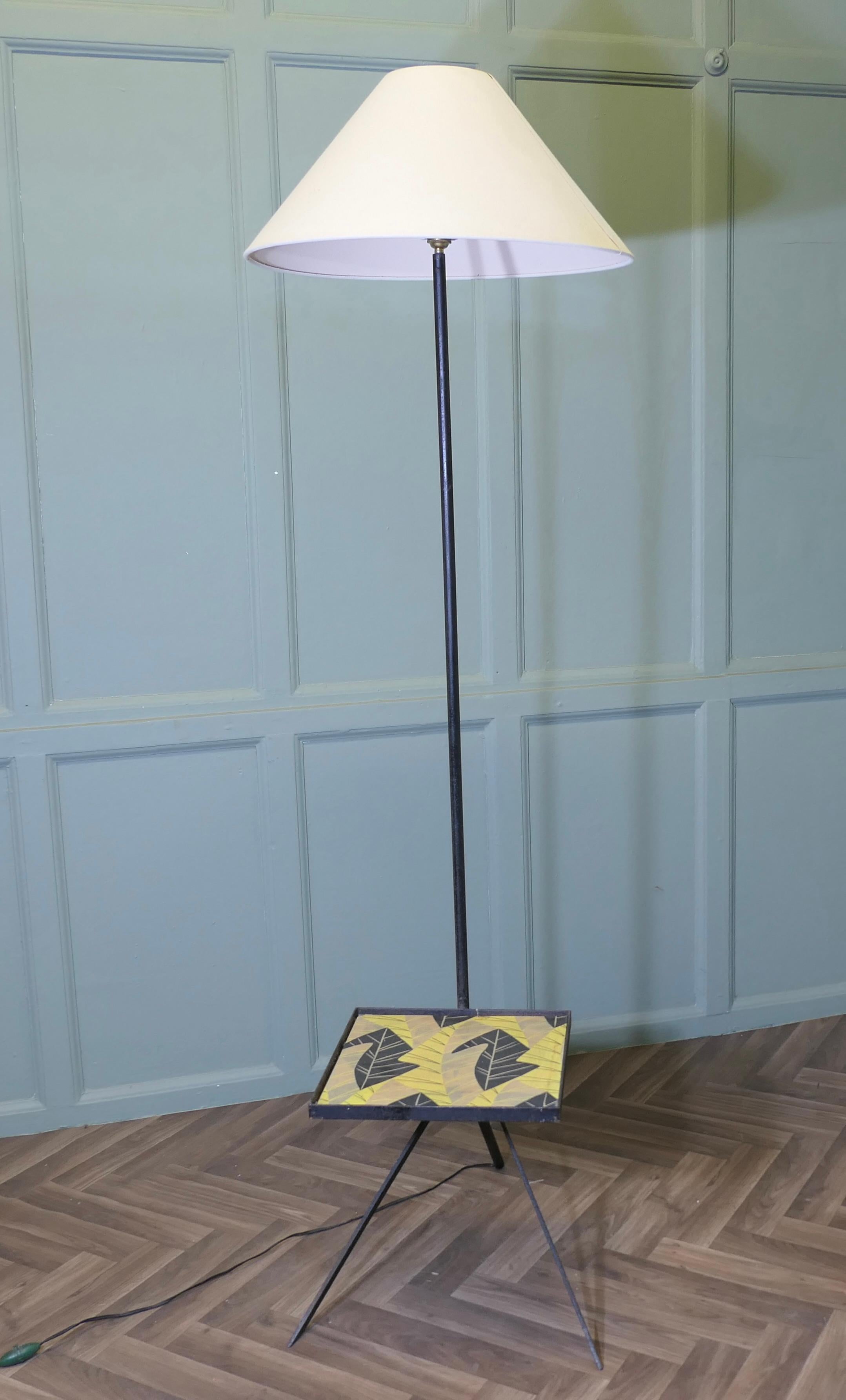 Lampadaire rétro chic des années 1950 avec table basse

Il s'agit d'une pièce inhabituelle, la lampe a un cadre en métal, elle repose sur 3 pieds évasés et a une table basse, d'où s'élève un lampadaire minimaliste. 
La lampe est équipée d'un nouveau