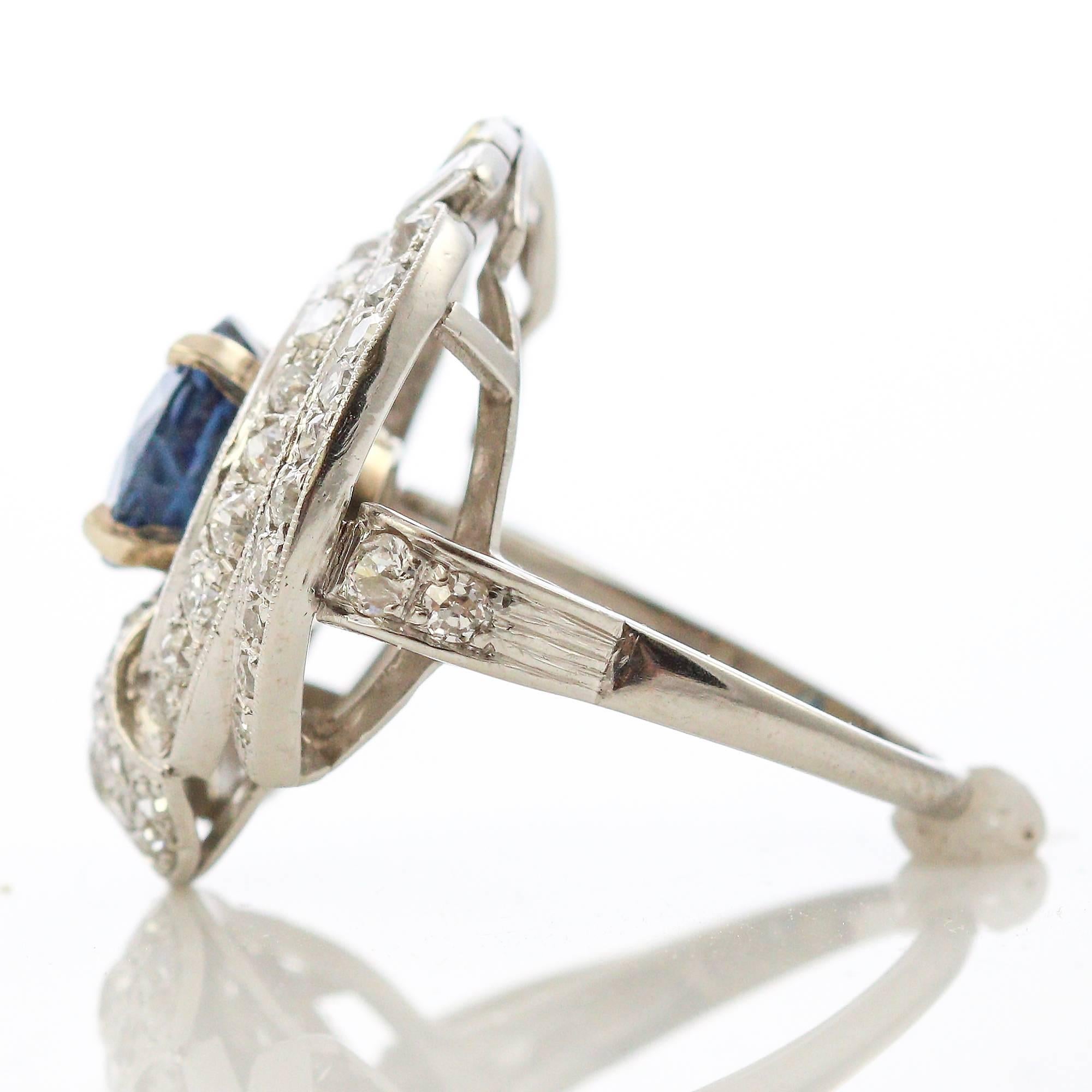 Im Mittelpunkt dieses witzigen Rings steht ein runder blauer Saphir (ca. 2,00 ct), der in Platin gefasst und von einem Design aus 66 Diamanten im alten europäischen Schliff und 6 Diamanten im Baguetteschliff umgeben ist. Die Diamanten wiegen