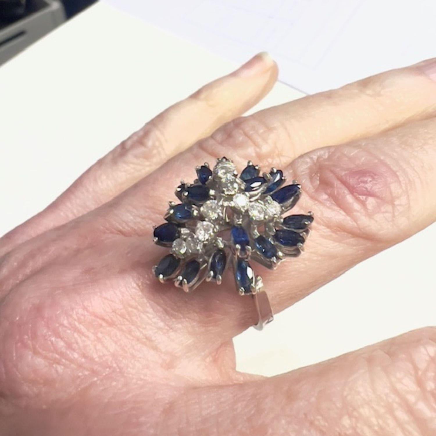 Questo anello retrò degli anni '50 è realizzato in oro 18 carati e presenta diamanti a taglio brillante e zaffiri a taglio navette. Il peso è di 6,37 grammi e la taglia è ES 16,5 / EU 56,5 / US 7,75. L'anello è impreziosito da diamanti a taglio
