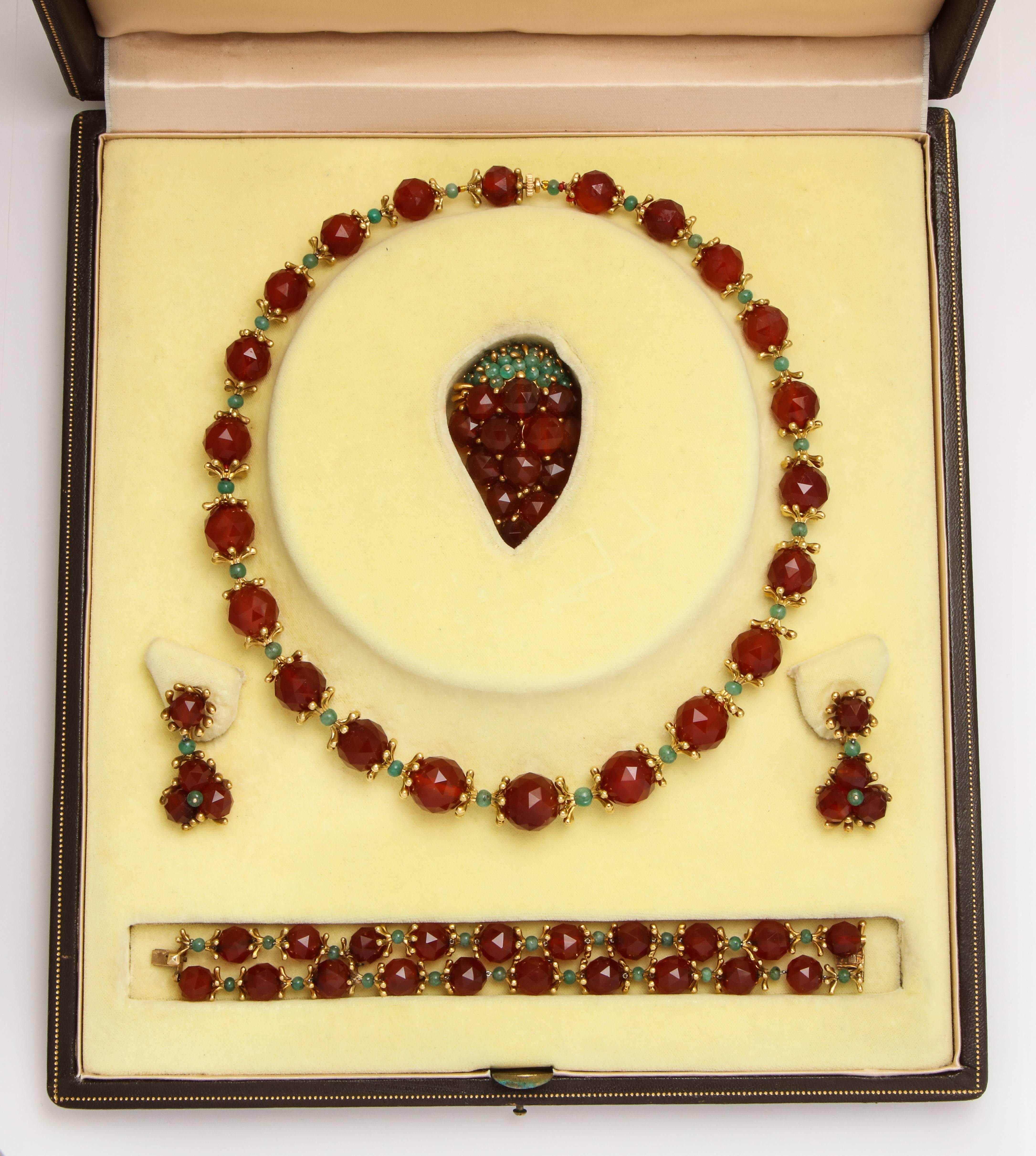 We offer a beautiful one-of-a-kind 1950's jewelry suite by designer Robert Barre using rich amber-colored faceted carnelian beads with 18K gold caps of modern organic form separated by emerald beads comprised of a double strand bracelet, graduated