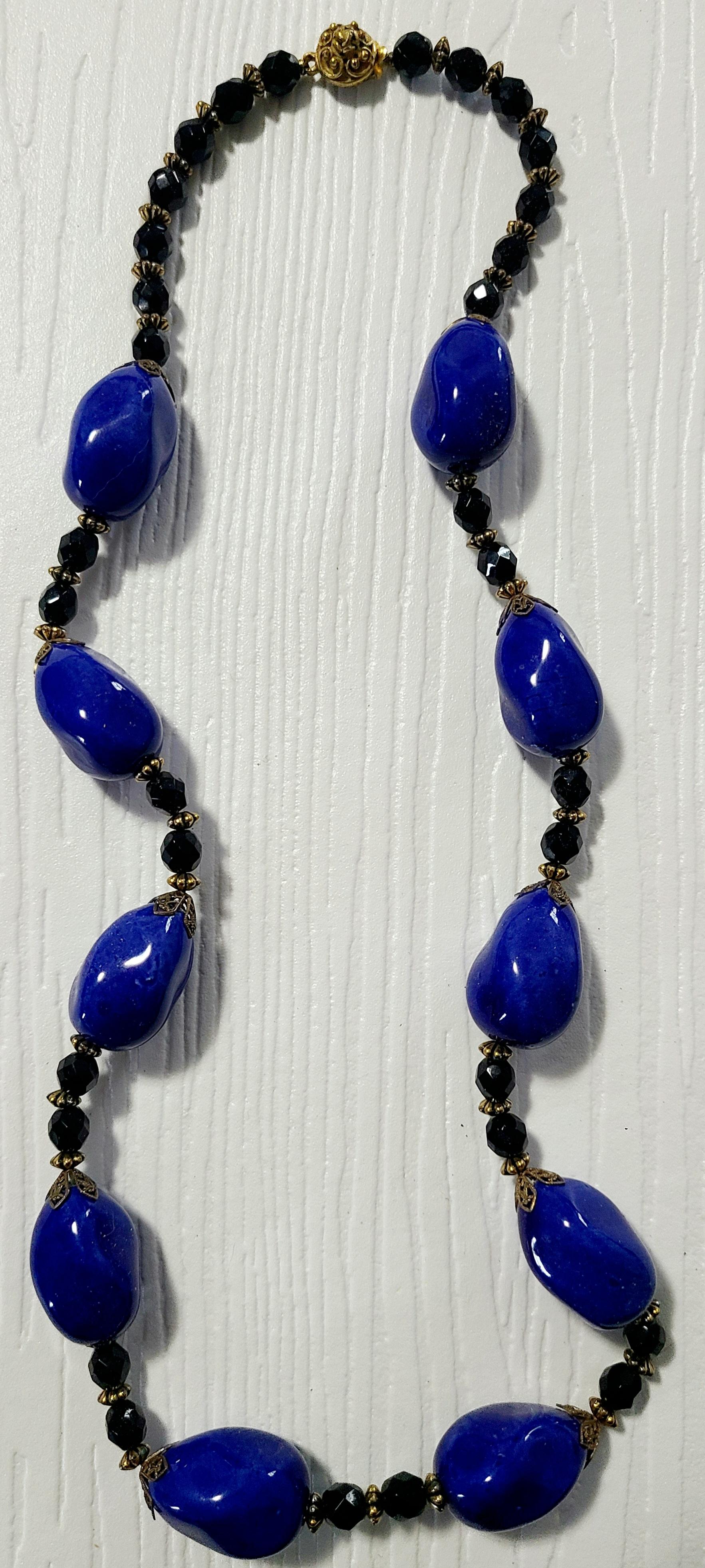 Hand-blown glass cobalt beads and black spinel beads are hand strung in this statement piece from the Early 1950s.

The history of the brand “Original by Robert” dates back to 1942. Founded by Robert Levy, David Jaffee, and Irving Landsman as