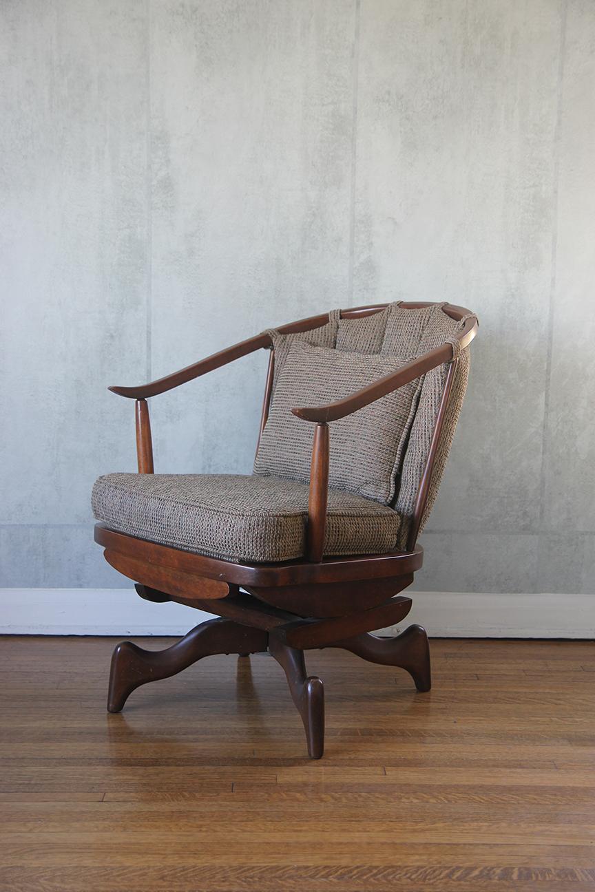 Presentamos una impresionante mecedora giratoria, elegantemente tapizada en la exquisita tela Sina Pearson. Esta silla capta la esencia de la estética moderna predominante en las oficinas corporativas estadounidenses de la posguerra, caracterizada