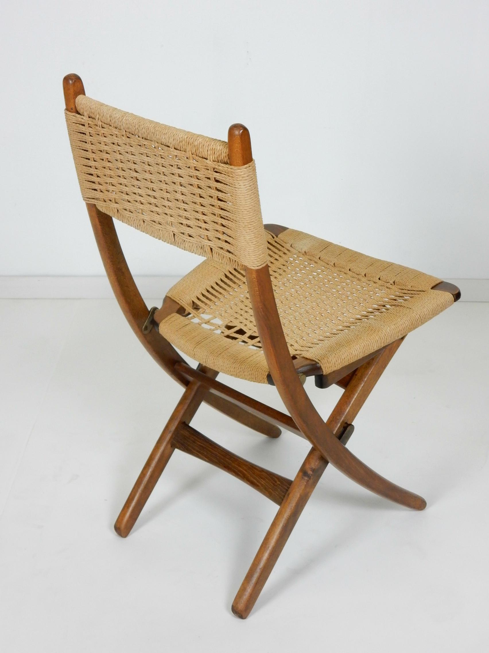 Set of 4 rope upholstered scissor chairs, circa 1950s
in the style of Danish designer Hans Wegner. 
Each folds for ease of storage.
Brass hardware with natural rope woven seat and back.
All are in very good condition with no damage or repairs.