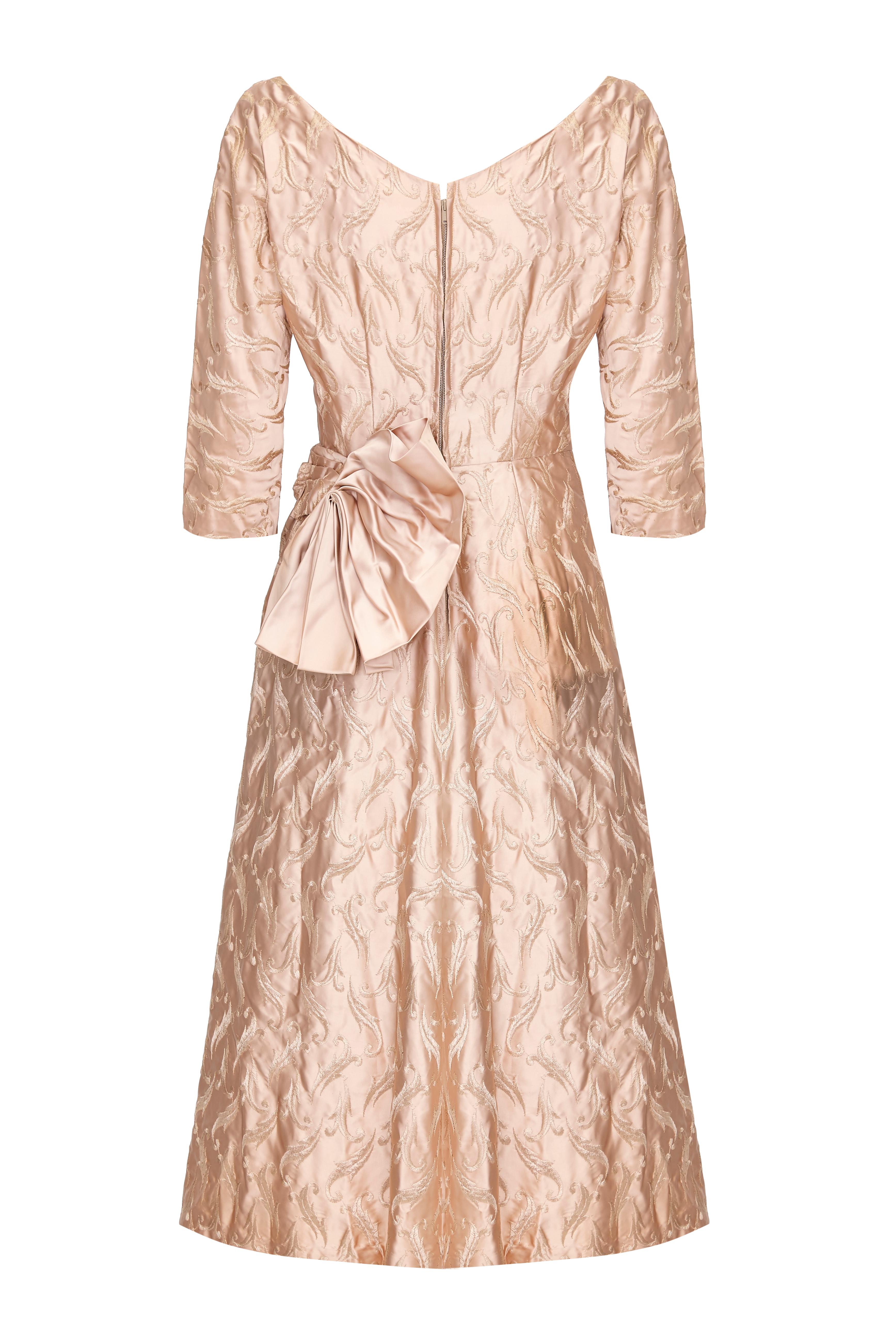 Magnifique robe vintage des années 1950 de fabrication américaine en satin antique or rose avec broderies sur l'ensemble du corps.  Cette jolie pièce présente des manches trois quarts, un décolleté en cœur, un jupon en tulle pour plus de volume, un