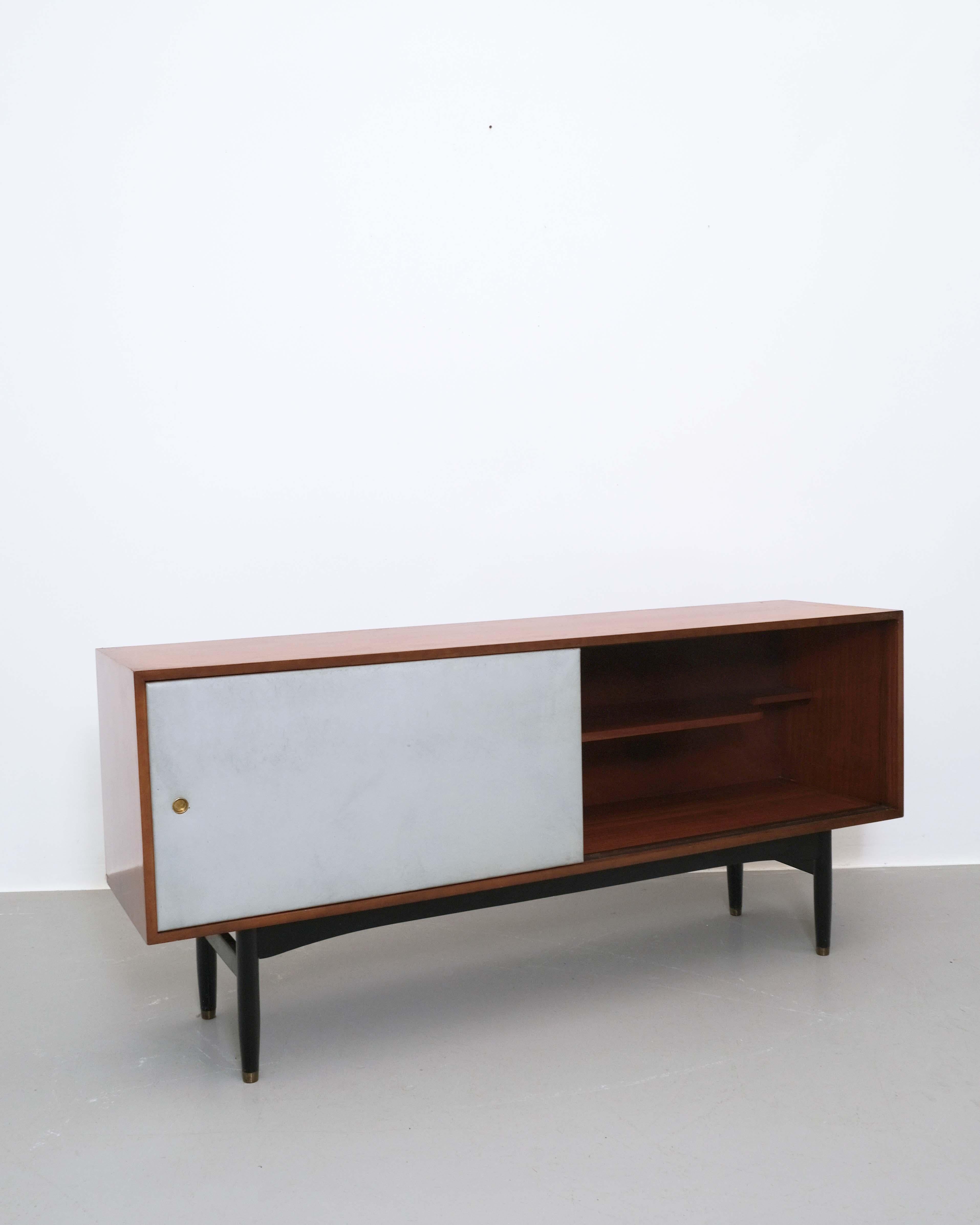 Una straordinaria credenza del famoso designer britannico Robin Day, risalente agli anni Cinquanta. Realizzato con un corpo in legno di palissandro, gambe ebanizzate e ante scorrevoli in pelle, questo pezzo esemplifica l'approccio pionieristico di