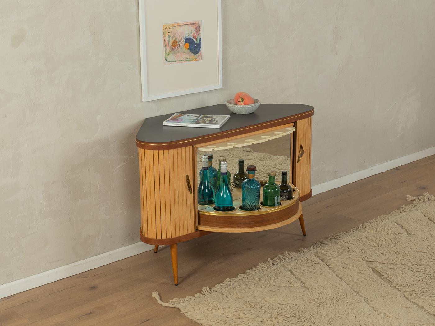 Wonderful corner cabinet from the 1950s with integrated bar compartment. High-quality corpus in walnut/ash veneer with two tambour doors, revolving bar compartment with glass and bottle holders and tapered feet. Designed and manufactured in