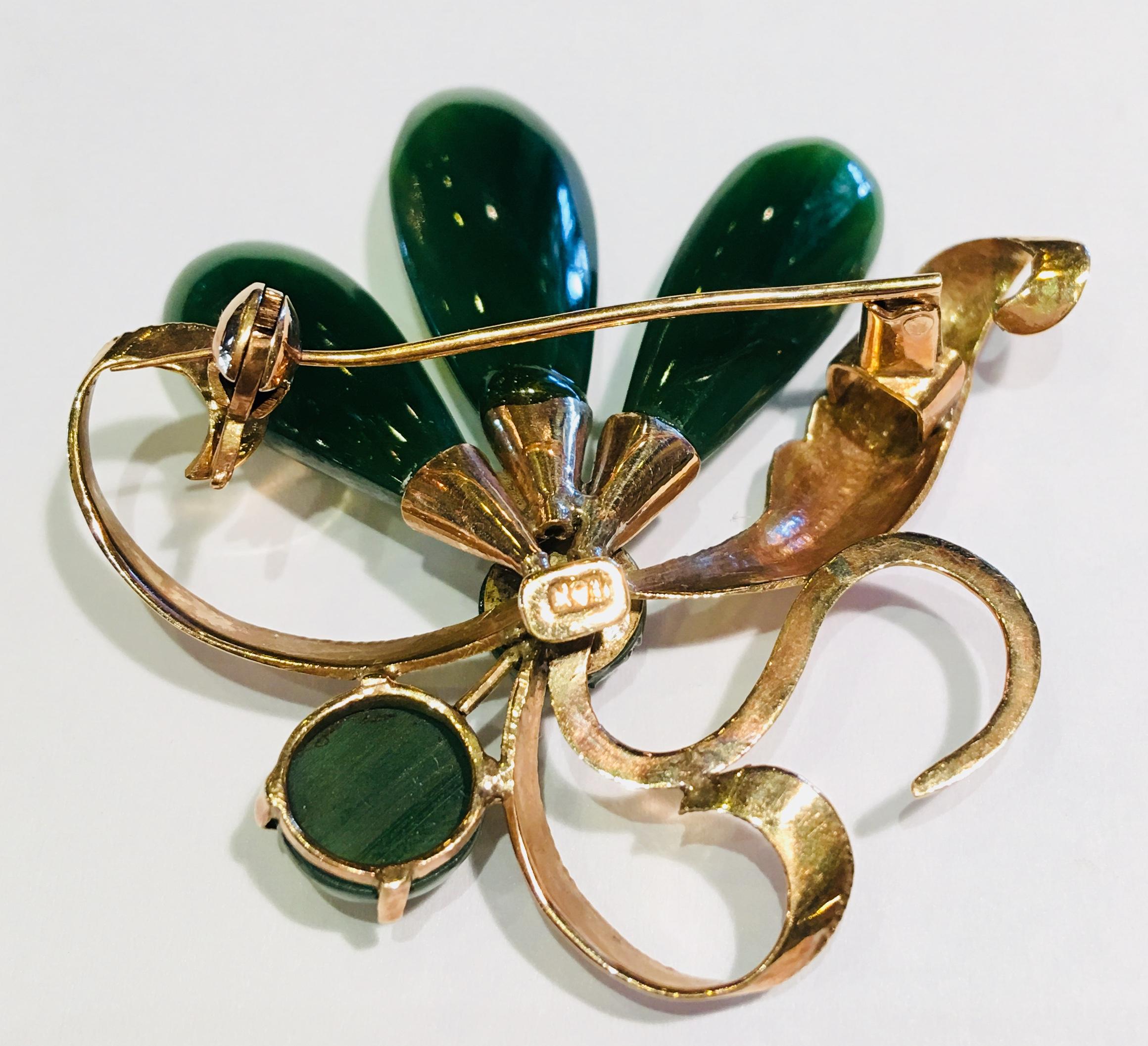Lovely vintage brooch pin from the 1950s features 2 round green jade pieces and 3 teardrop shaped green jade pieces to form an abstract flower, set in 18 karat rose gold and accented by a long, curling etched leaf and 3 similar abstract