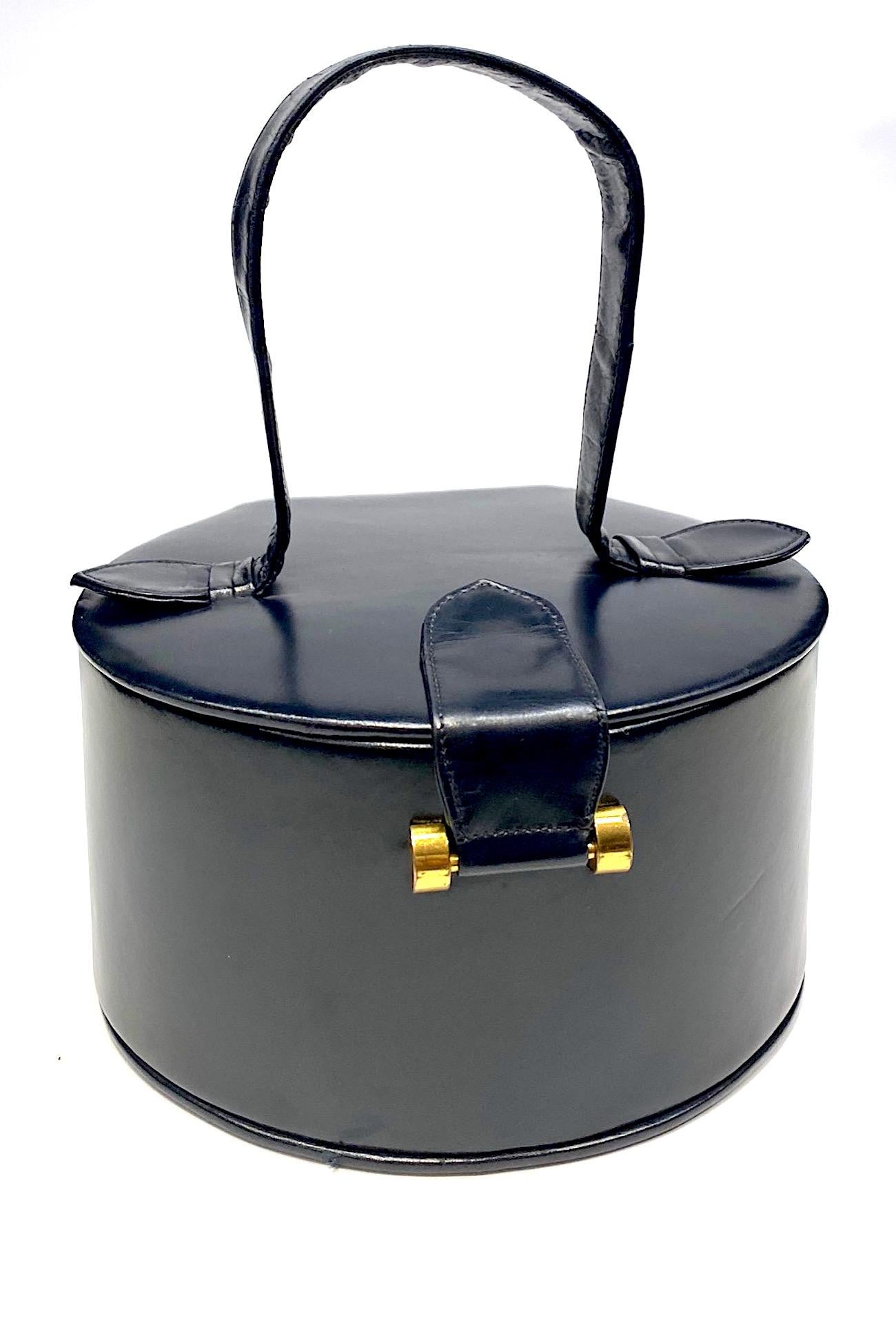 1950s Calf leather round box bag in midnight navy blue by Theodor of California. The company open in 1946 and filed for trademark in 1954. Theodor is no longer in operation for many years now. The bag is 6.75 inches wide, 6 inched deep from front to