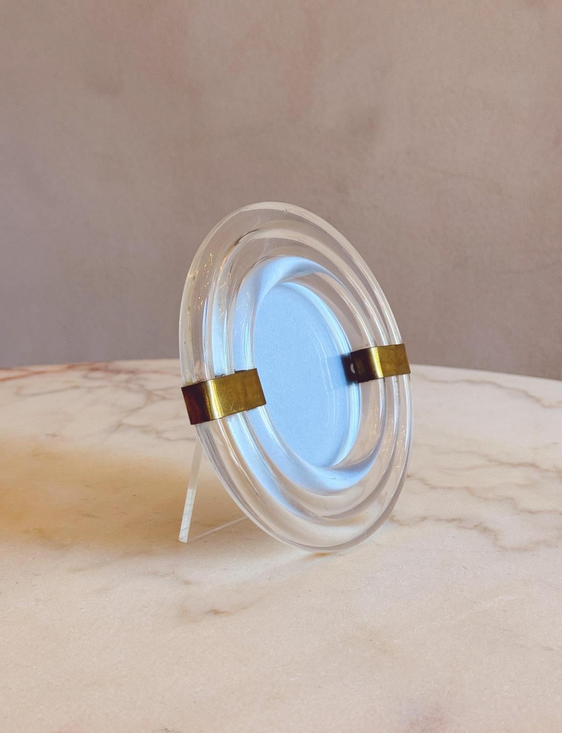 Ein sehr hübscher italienischer Fotorahmen aus Plexiglas und Messing. Dieser Rahmen eignet sich perfekt für ein kleines rundes Foto auf dem Schreibtisch. Sie besteht aus drei konzentrischen Plexiglasröhren, die auf beiden Seiten von hübschen