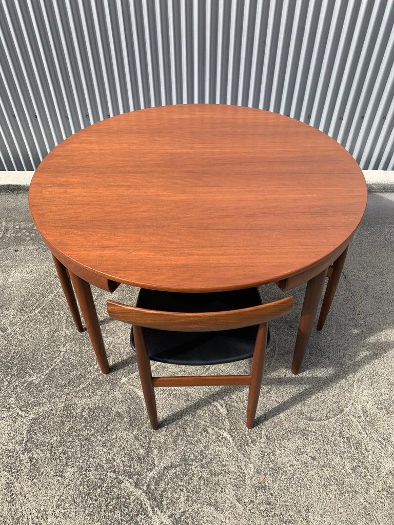Iconic Hans Olsen design. 4 chairs tuck neatly under table top to complete the underside of the top. Beautiful grain pattern on the sides of the legs, top and chair backs.