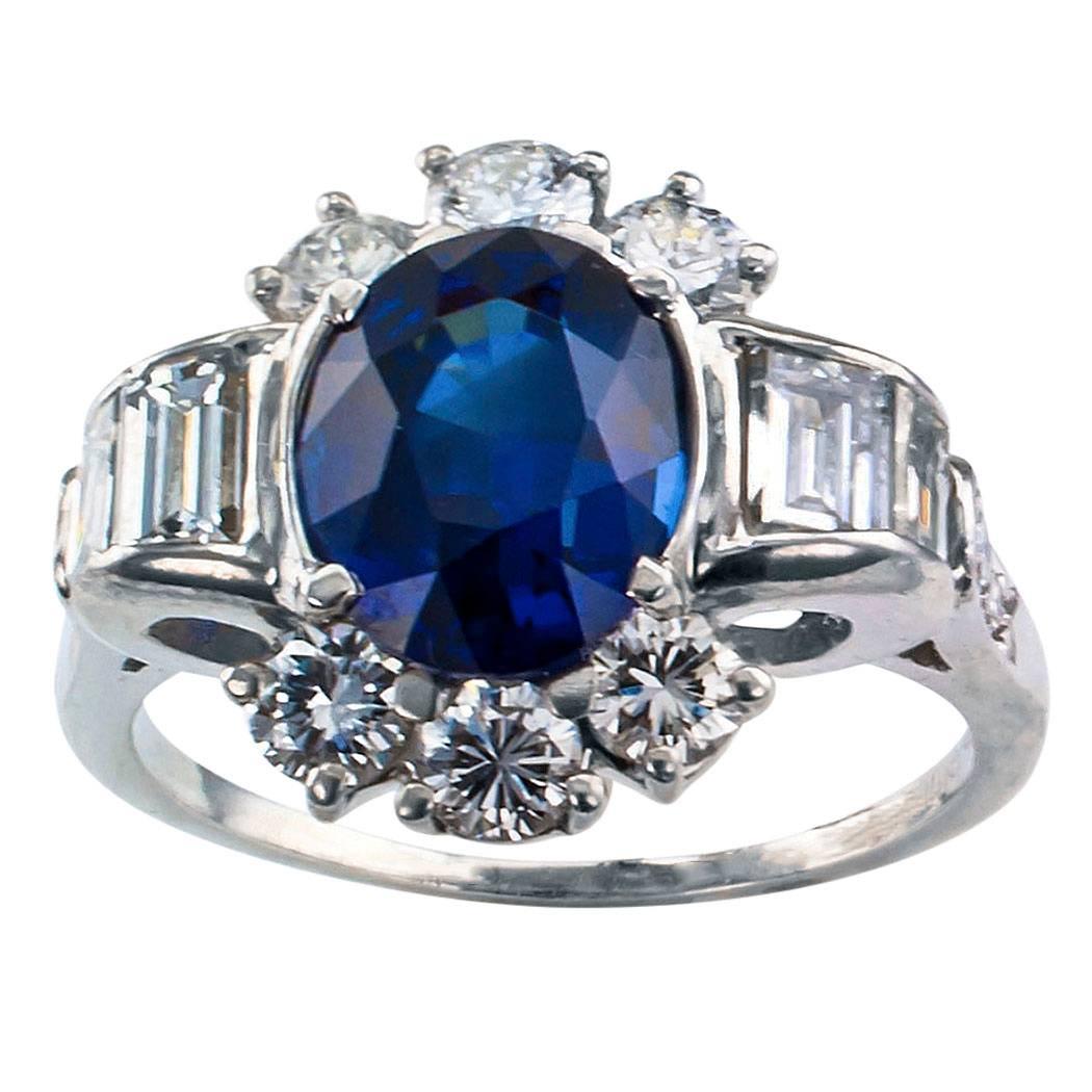Mid century 1950s sapphire and diamond platinum ring. Centering upon an oval blue sapphire weighing 3.58 carats, accompanied by a report from GIA stating that the sapphire is Royal Blue Color, framed by trios of round brilliant-cut diamonds to the