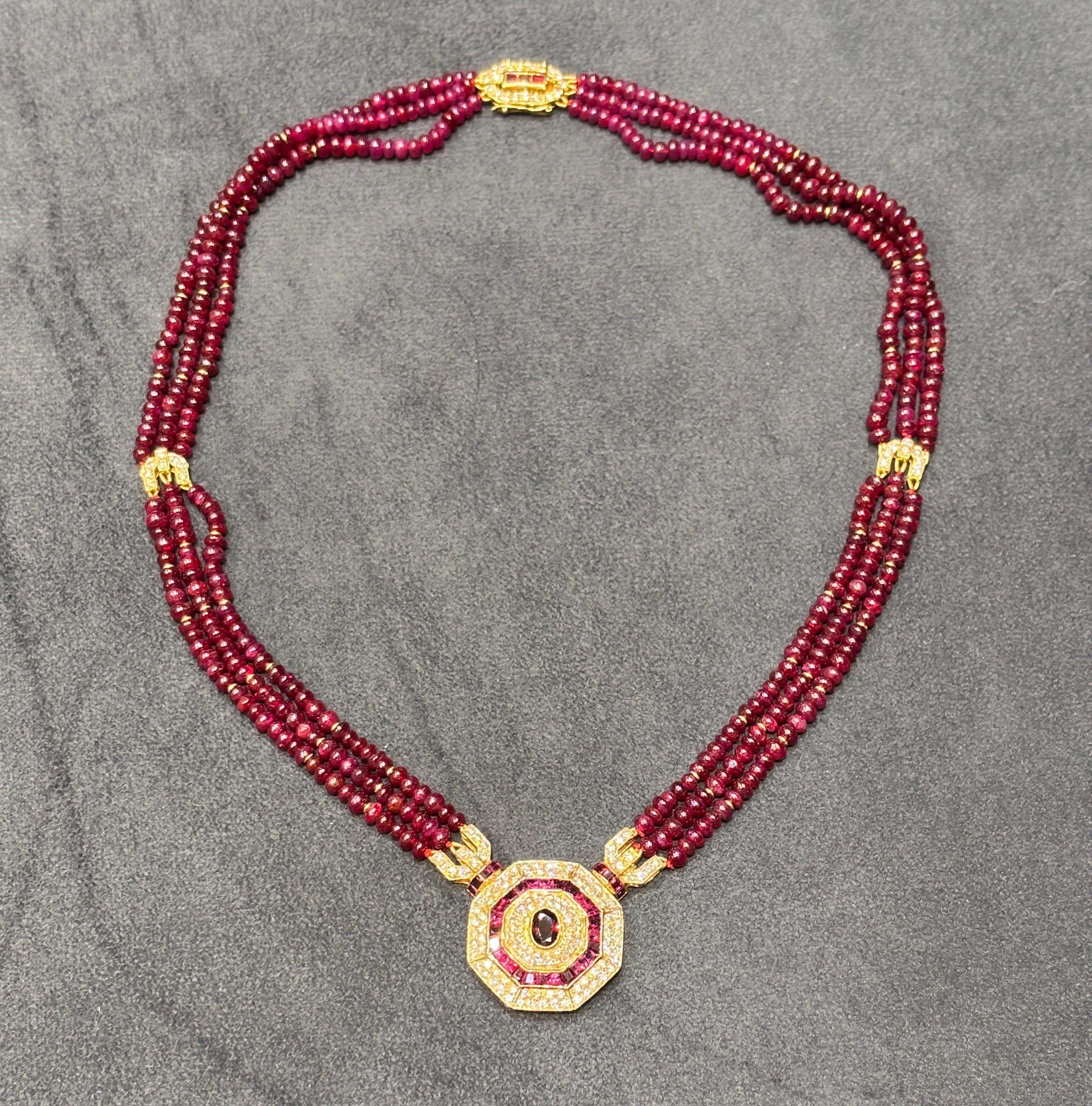 This beautiful necklace has an octagon shaped pendant the design of which is centred around an oval faceted ruby. The central ruby is surrounded by round cut diamonds. An octogan of tapered baguette and princess cut rubies encircle the diamonds and