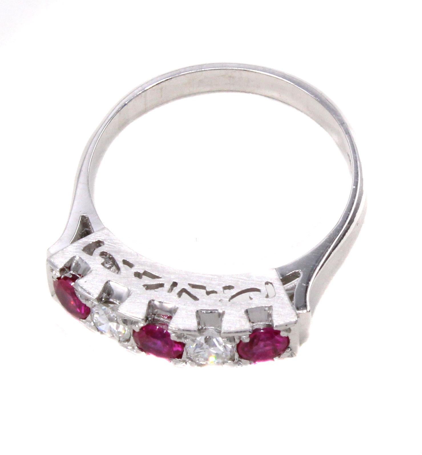 This finely handcrafted platinum 1950s ring features 3 vivid red round rubies spaced by 2 bright white round cut diamonds. An amazing contrast of color, beautifully set on a gallery with decorative a jour work with a mat polish. Ring size 5, can be