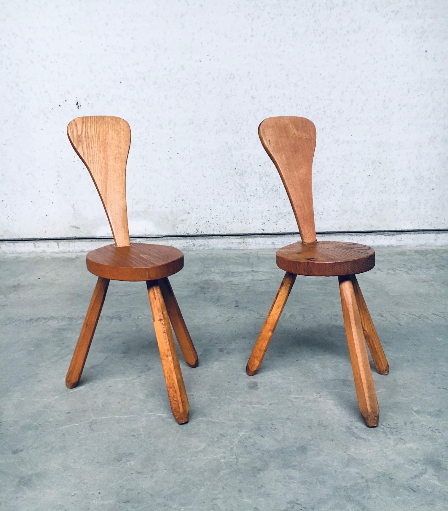 Vintage Rustic handcrafted Brutalist in style oak milk stool set. Made in Belgium, 1950's / 60's. Solid oak wood constructed stools. Both are in very good, original condition. The back rest has been reglued at some point in time by the previous