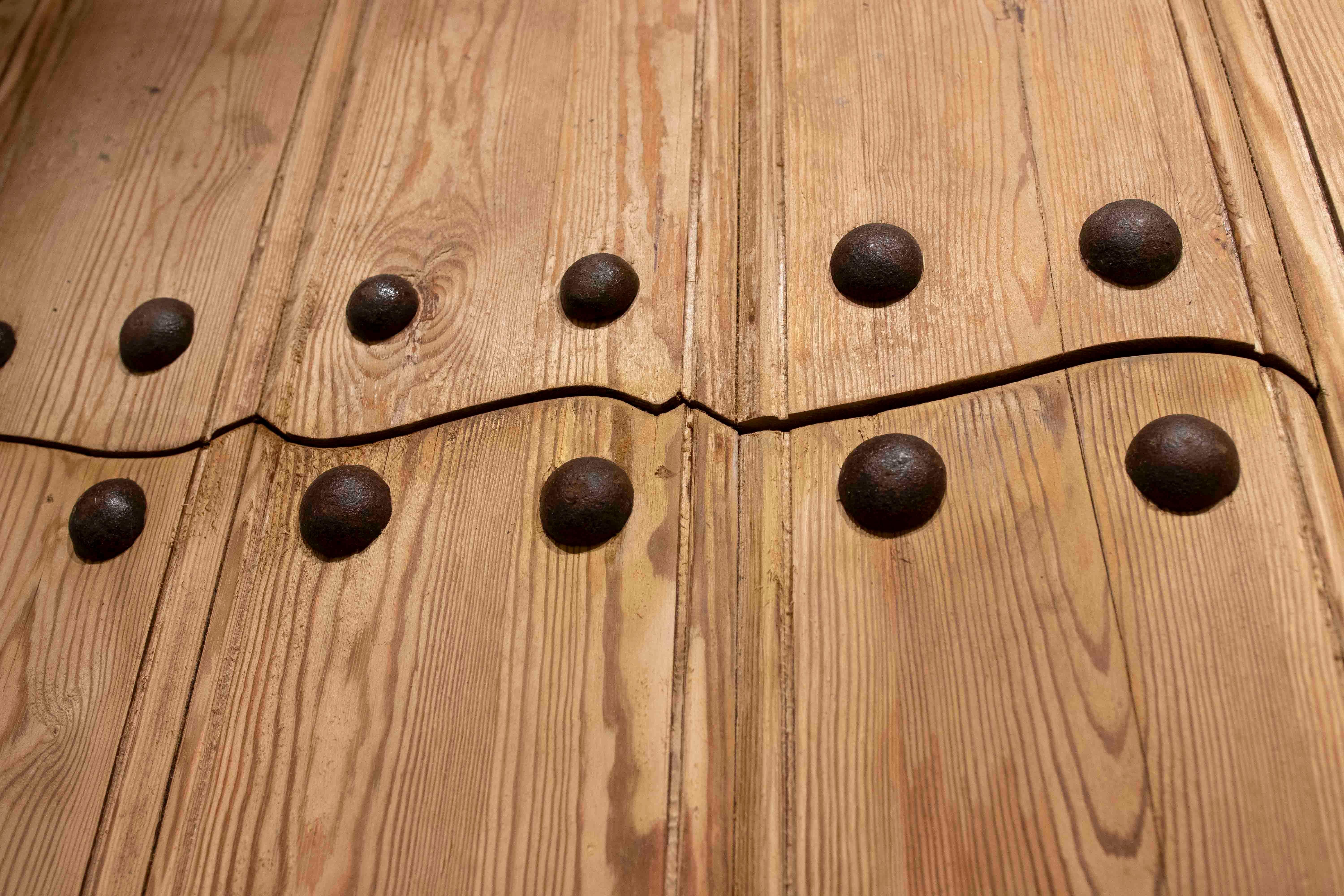 Puerta rústica española de madera de los años 50 con clavos forjados y reja central de hierro siglo XX en venta