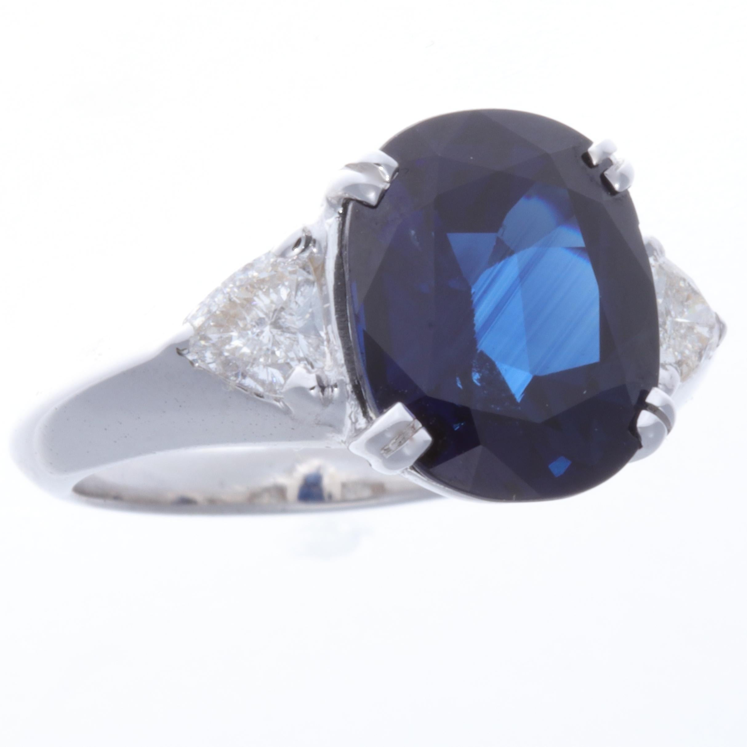 The 1950's, a time of new beginnings and idealism adding sophistication and structure to life. Represented in this this sparkling vivid blue sapphire set in a robust gold ring. The cushion cut sapphire weighs 5.85 carats, accented with two trillion