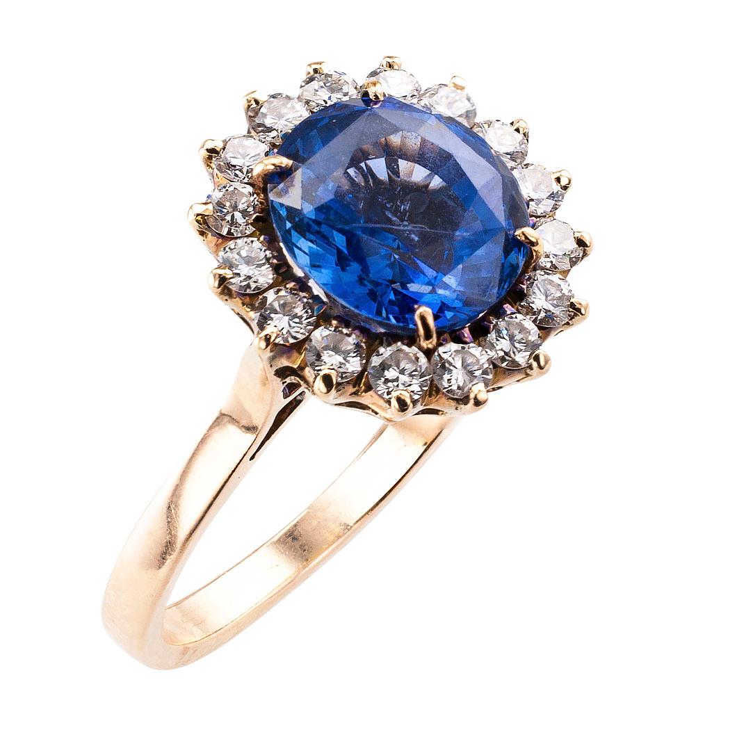 Mid century sapphire and diamond gold ring circa 1950. The design showcases a round sapphire weighing approximately 3.25 carats, set within a conforming border comprising sixteen round brilliant-cut diamonds totaling approximately 0.50 carat,