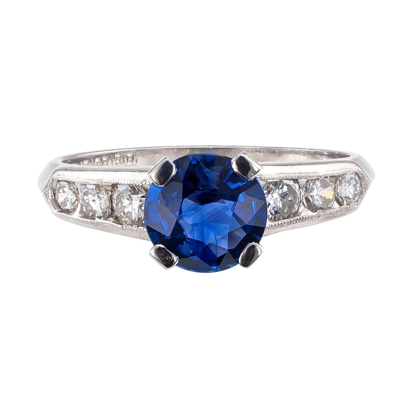  Sapphire and diamond platinum engagement ring circa 1950.

DETAILS:
GEMSTONES:  one round, faceted blue sapphire weighing approximately 1.0 carat.

DIAMONDS:  six graduating, round brilliant-cut diamonds totaling approximately 0.32 carat, H – I