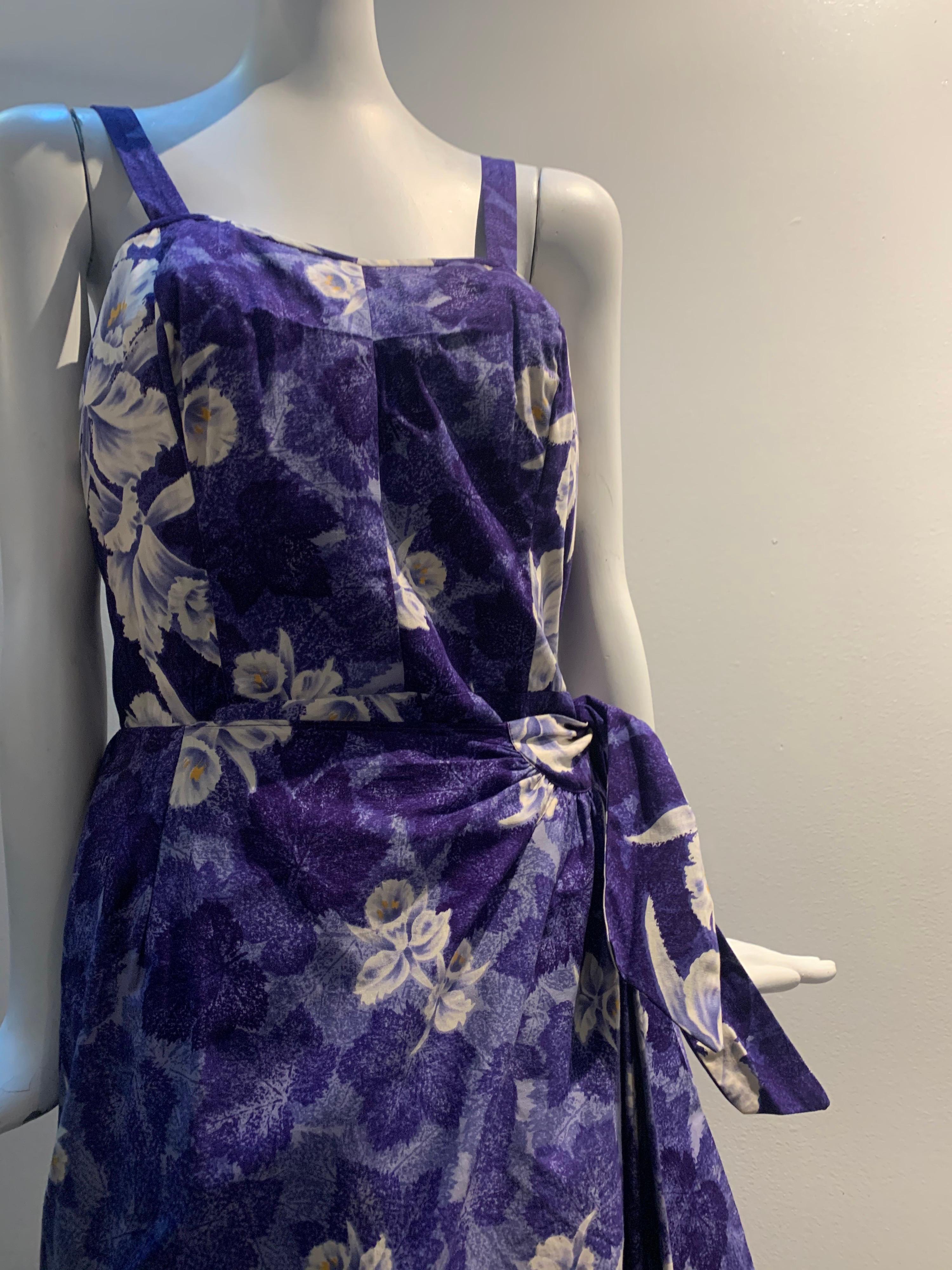 1950s Sarong-style cotton sun dress in purple tropical print with scattered white orchids. Back zipper, elasticized side panels, wrap skirt with side tie. Classic Dorothy Lamore style! Size 8.