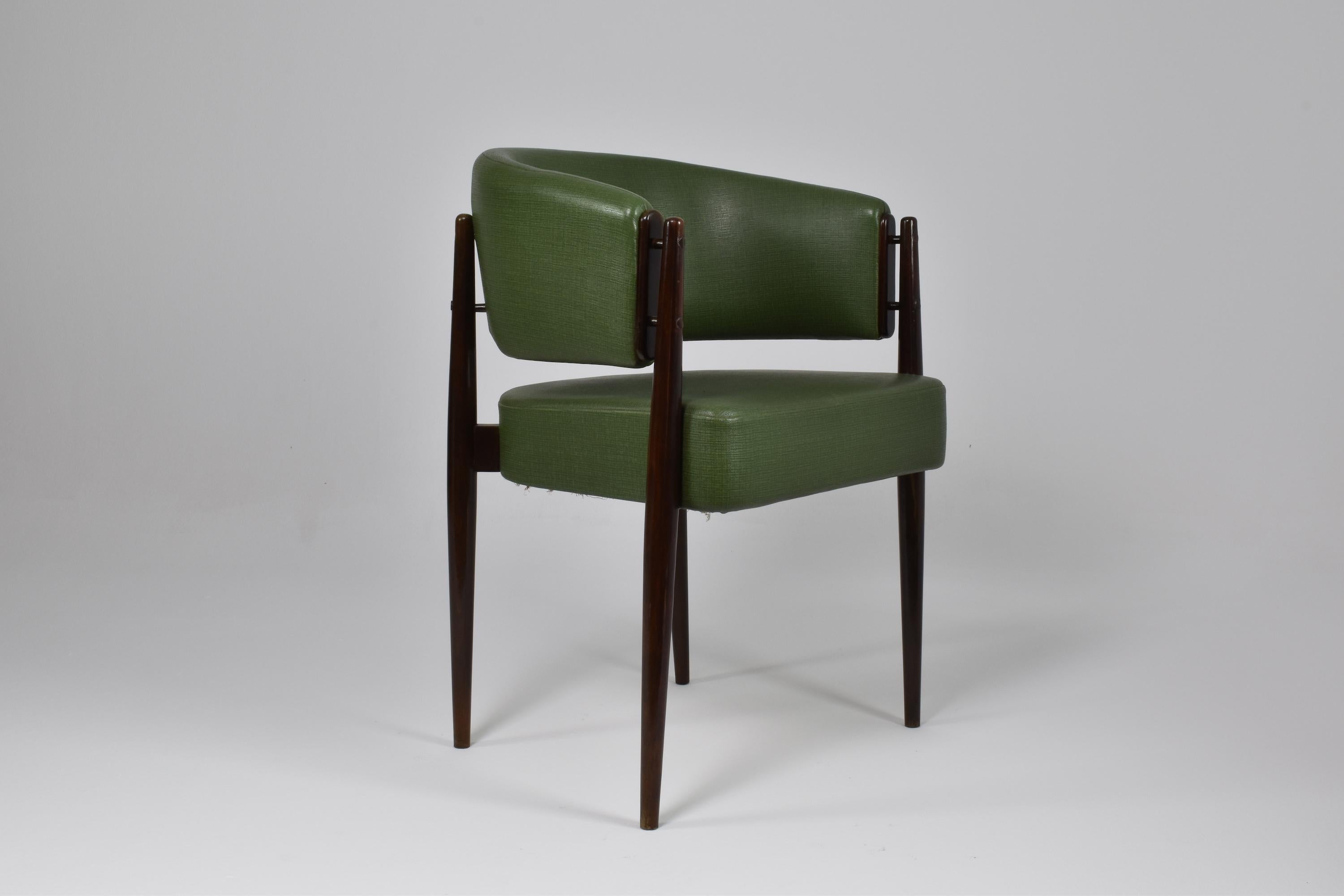 A 20th-century vintage side chair or club chair in it's original green faux leather upholstery and fine impeccably restored beechwood structure. This piece was selected for its beautiful design, comfortable seating with its circular backrest, and