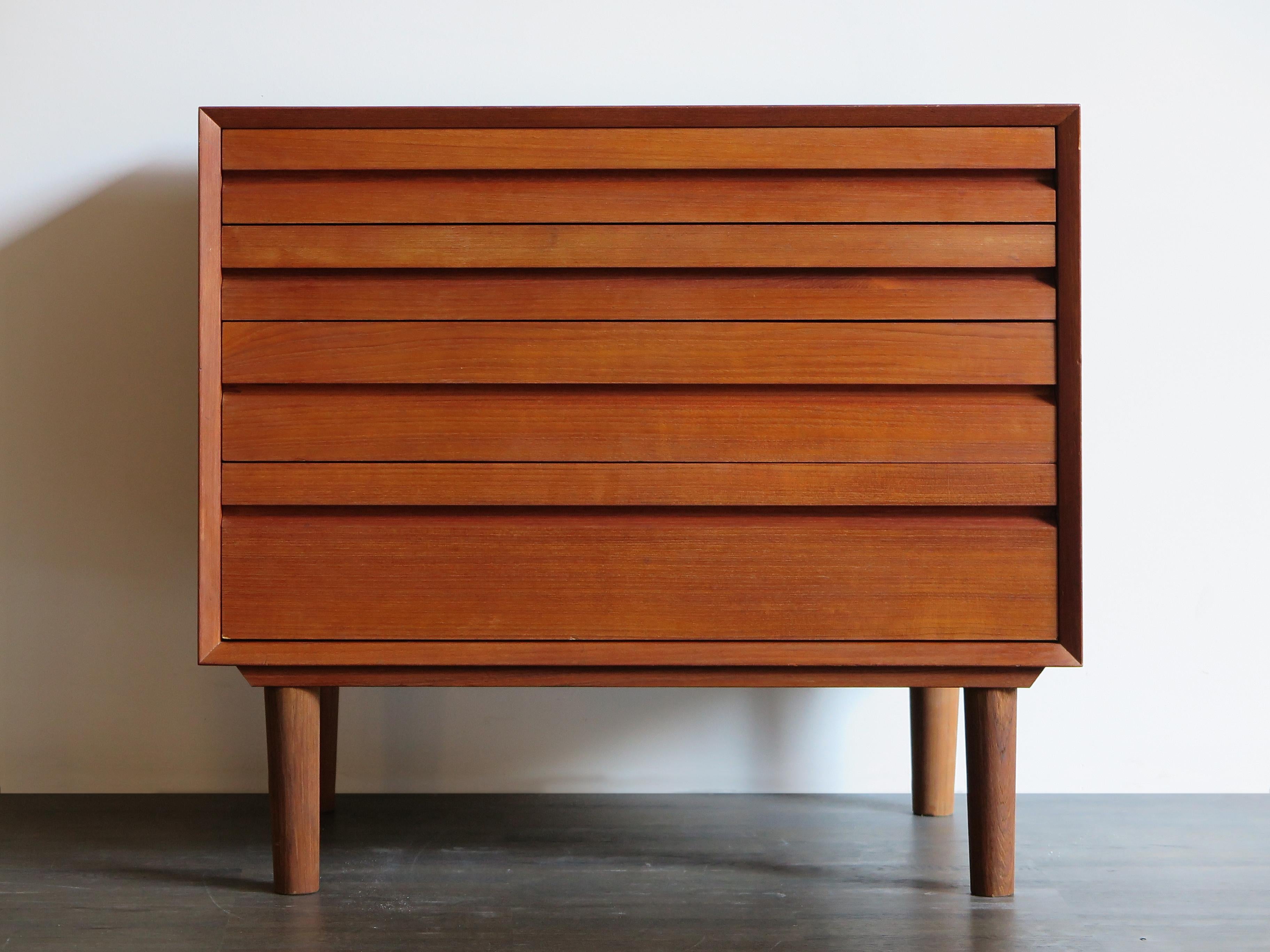 1950s Danish modern midcentury teak chest of drawers with four drawers that have different heights.