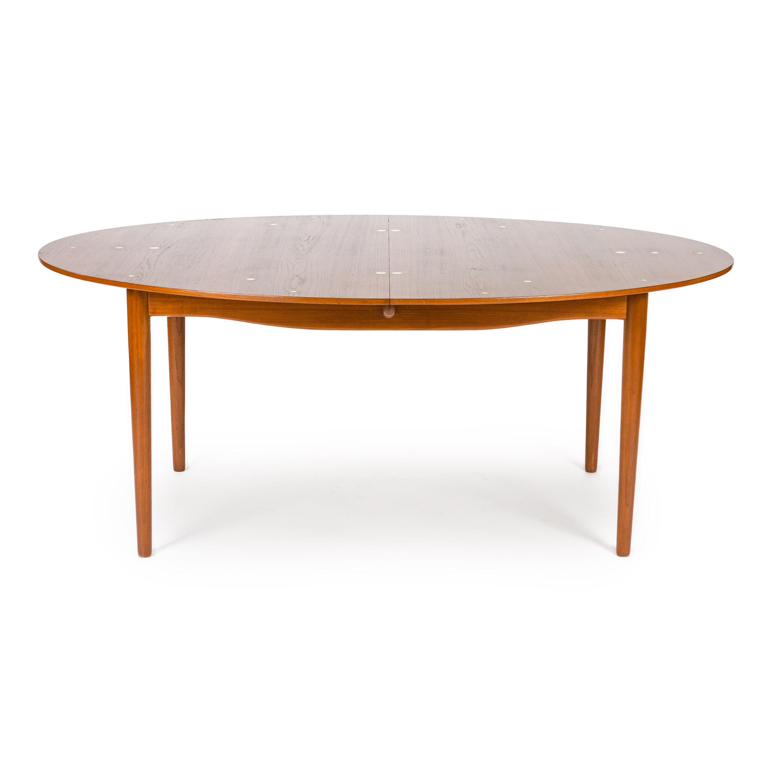 A rare and superb solid wood Judas dining table by Finn Juhl. Manufactured by Niels Vodder, the table features an expandable oval top (no leaves). Round silver inlays accents floating on a sculptural and architectural base with turned dowel legs.