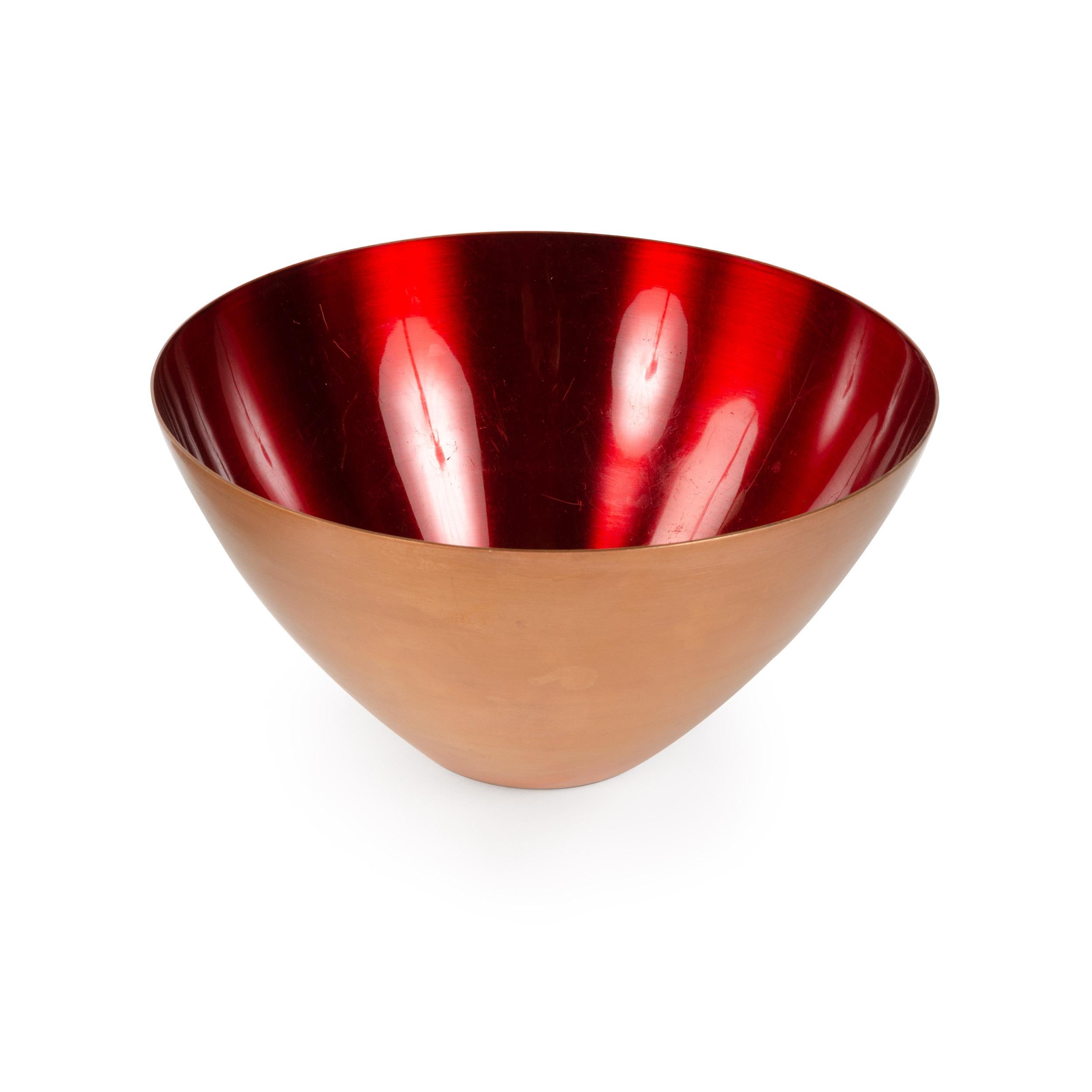 A large, deep spun copper bowl with flared exterior and vibrant red enamel interior.