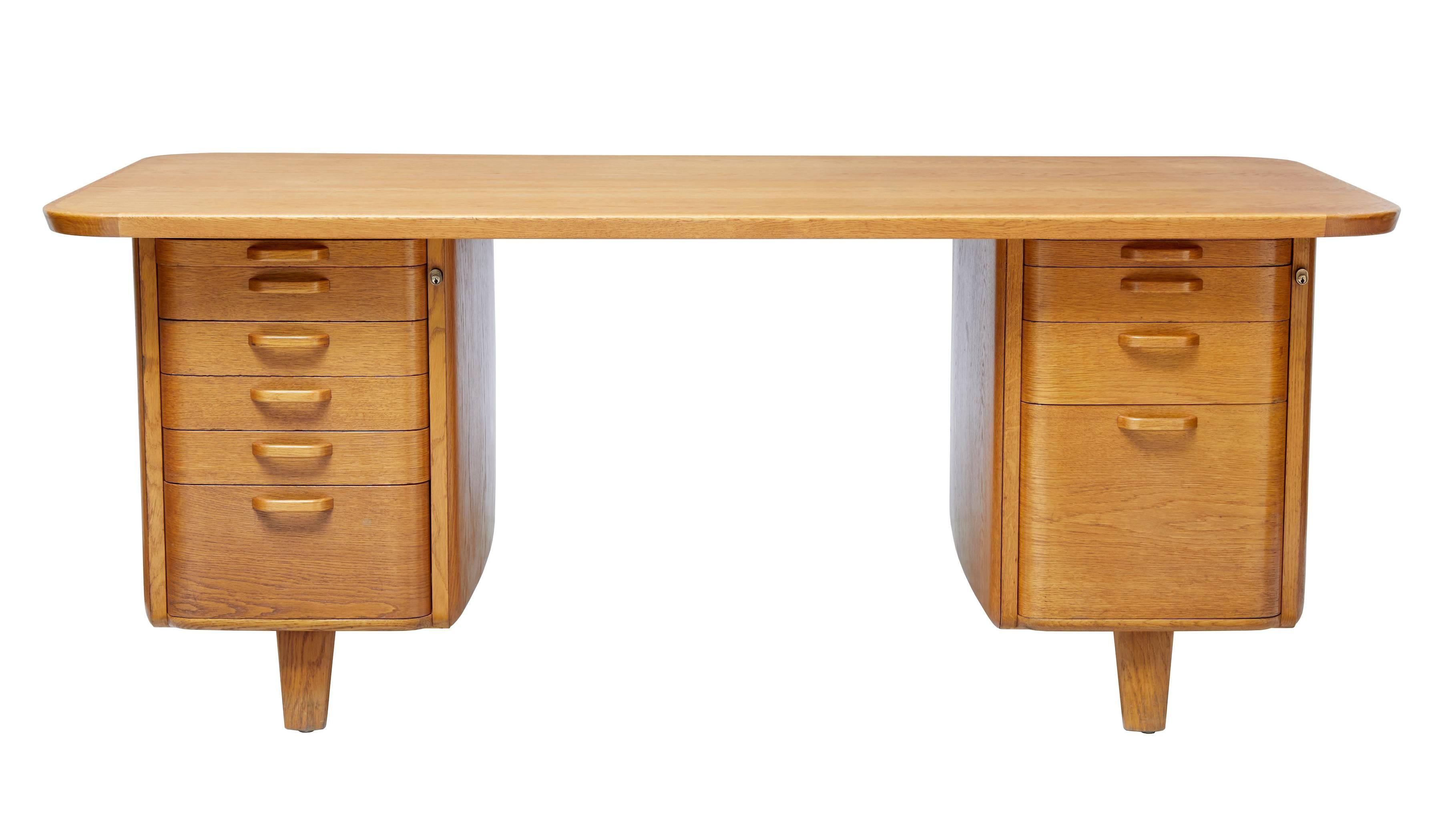 Fine quality late deco period desk, circa 1940.

Produced by Atvidaberg and designed by Gunnar Ericsson.

Rich golden oak woodwork used on this one-piece desk. Shaped pedestals with six graduating drawers to the left and four drawers to the