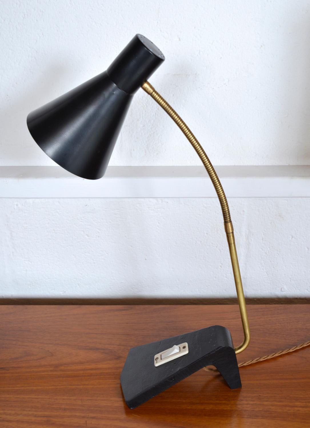 Lampe de bureau suédoise à col de cygne très soignée du milieu du siècle, avec un abat-jour en aluminium noir, un col de cygne en laiton et une lourde base en acier moulé de forme inhabituelle avec interrupteur. La lampe tient bien dans diverses