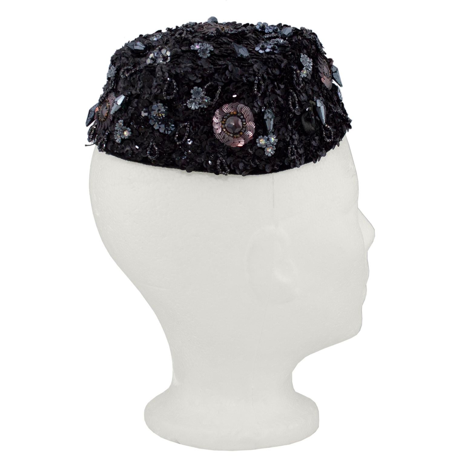 Schiaparelli black sequin and beaded evening hat/fascinator. Elegant accessory to wear or display with the unmistakable red script label. Two side combs to secure the hat at a rakish angle, multiple florets of sequin, bronze rosettes and dangling