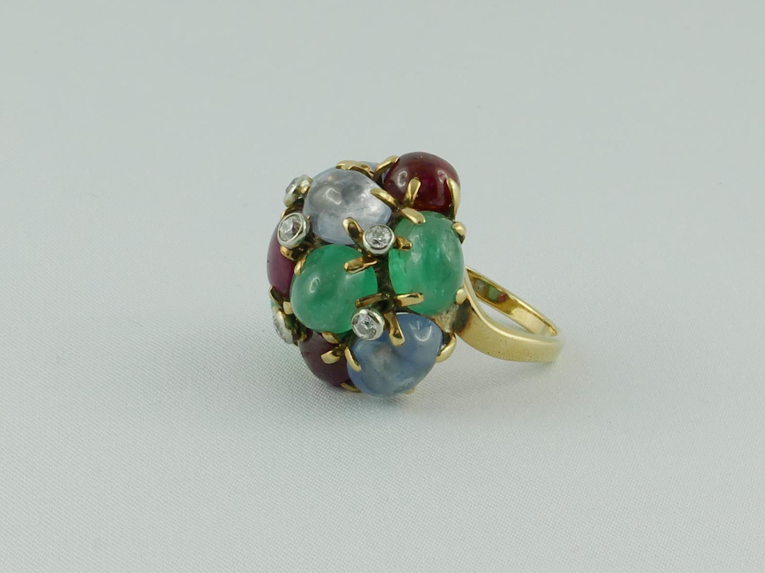 Retro TuttiFrutti Ring set  in 14 karat Yellow Gold with  3 cabochon Rubies, 3 cabochon Sapphires,  3 cabochon Emeralds and 5 diamonds, weighing a total of  14.5 Grams
This rare cocktail ring is an iconic piece of the famous jeweler Seaman Schepps.