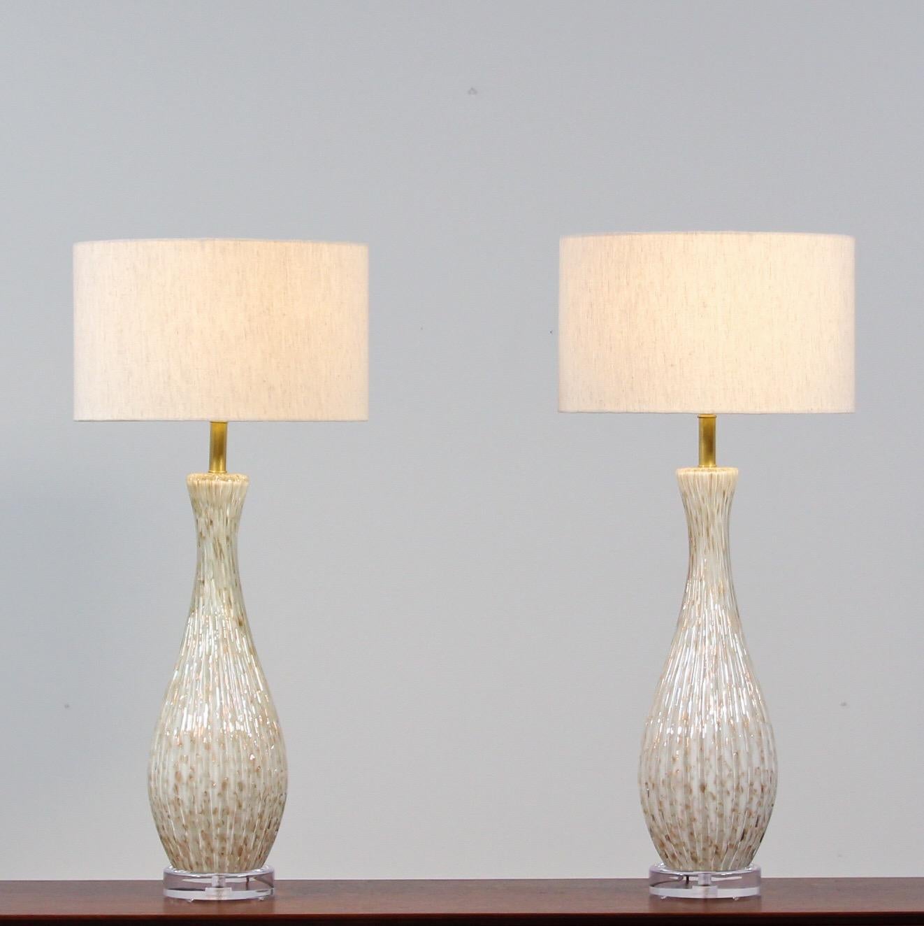 Impressive, 1950s pair of Murano glass lamps featuring a wonderful gold flecking and encased bubble (bullicante) technique on a white background by Alfredo Barbini. These beautiful lamps have been newly rewired. The brass hardware has been cleaned