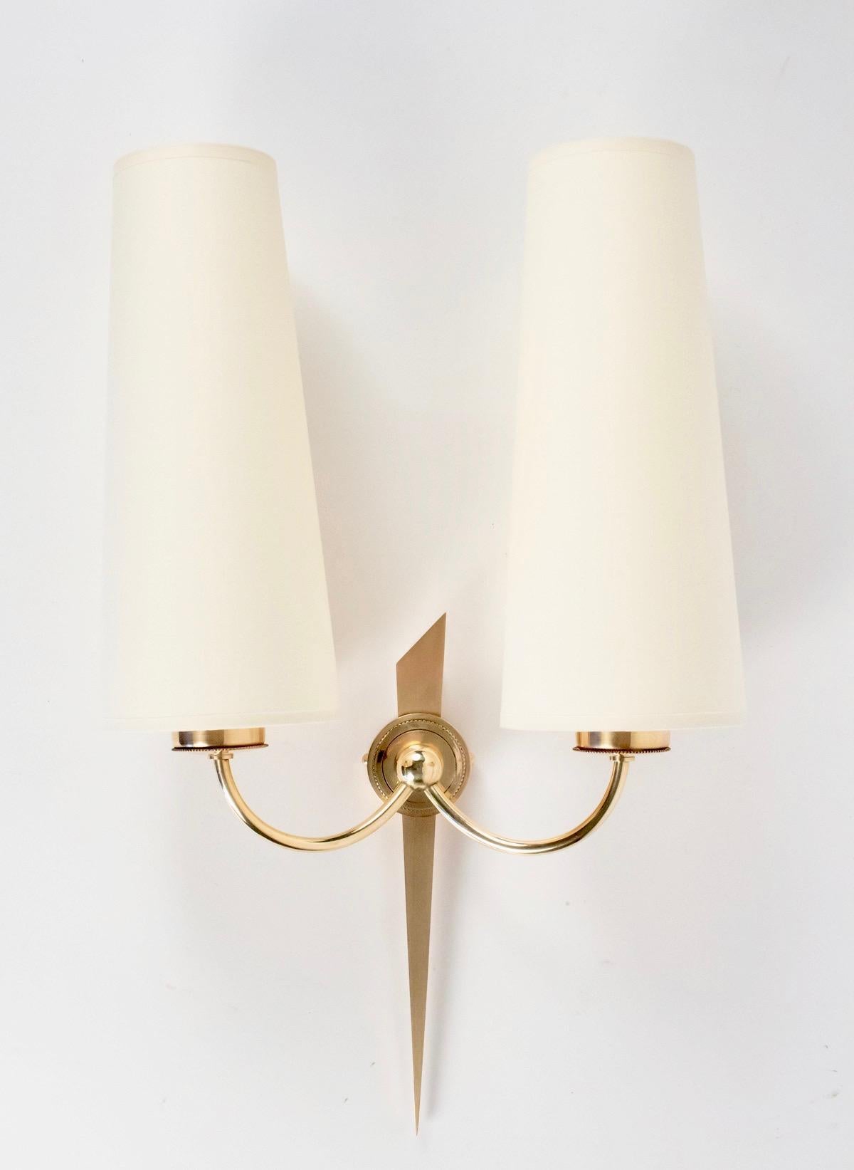 Elegant series of 4 wall lights from Maison Arlus in bronze and gilded brass.
Composed of an arm representing a stylized arrow made of a bronze coin.
The two light curved arms in gilded brass meet at the level of the central rod and are attached to