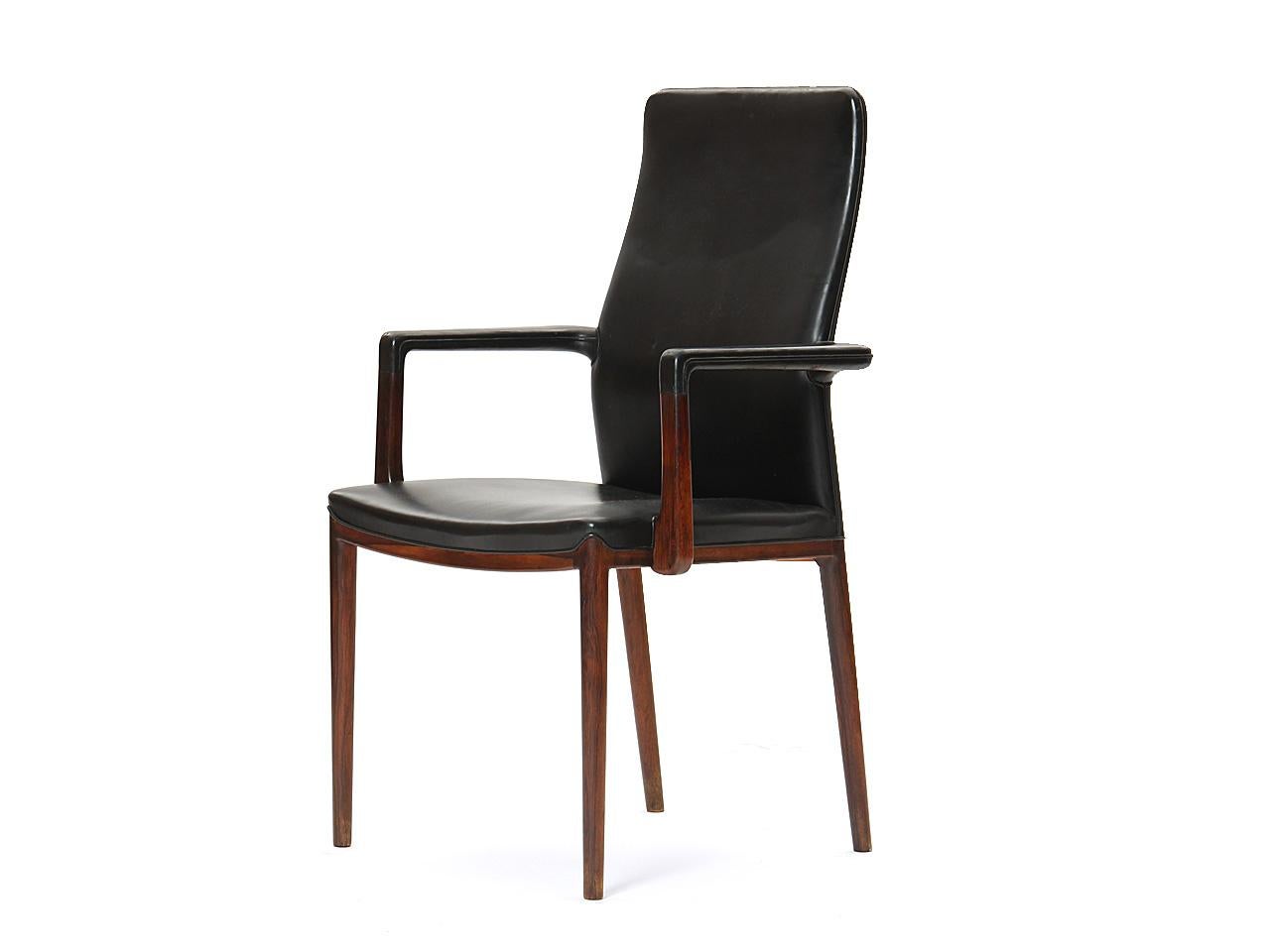 A rare and beautiful set of 8 sculptural rosewood dining chairs retaining their original black leather; there are six side and two armchairs in the set. Designed by Helge Vestergaard Jensen, and made by cabinetmaker Peder Pedersen.
  