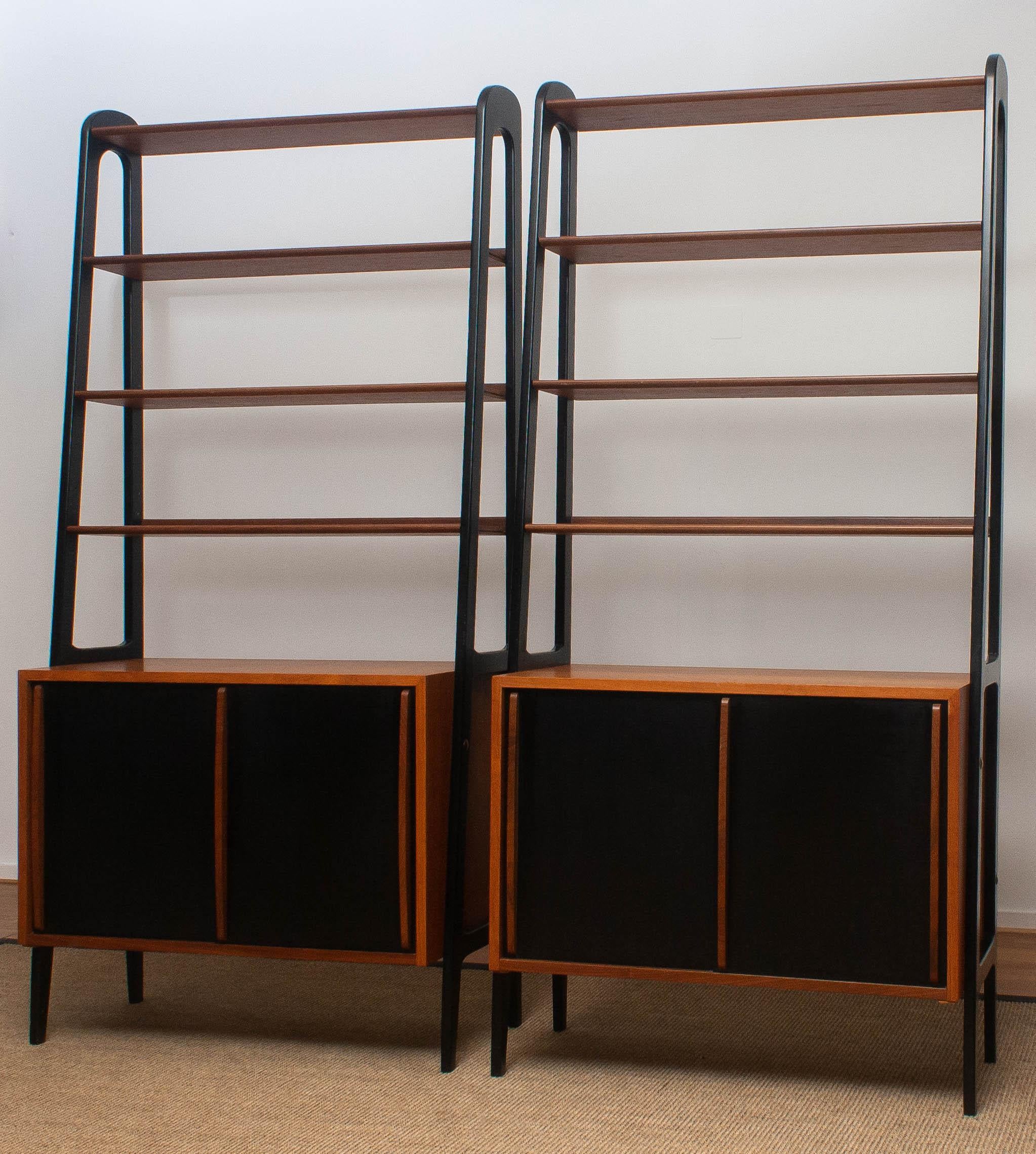 Two beautiful cabinets made of teak with black sliding doors and stands.
Because the cupboard is pretty slim and open to form it is also very suitable to use it as a room divider.
Each cabinet contains four shelves and a two-sliding door