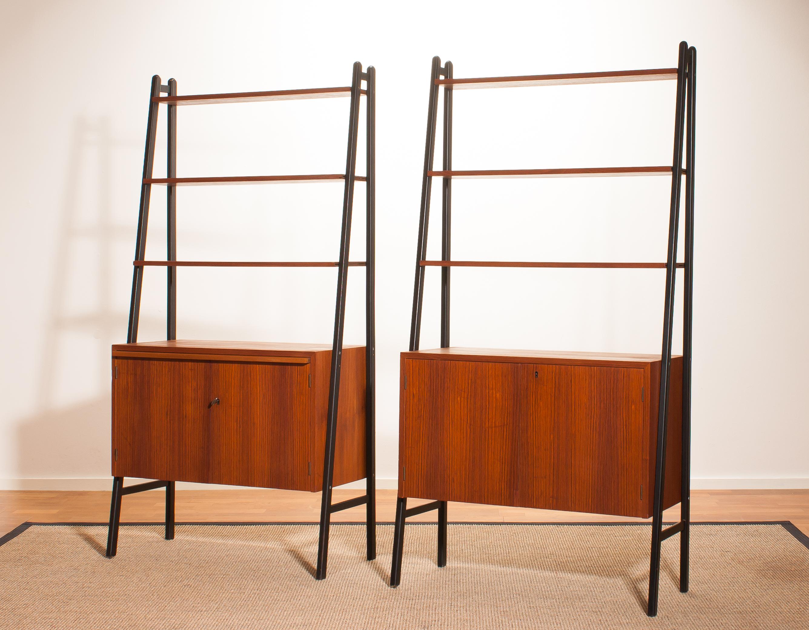 Two beautiful cabinets made of teak with black stands.
Because the cupboard is pretty slim and open to form it is also very suitable to use it as a room divider.
Each cabinet contains three shelves and a two-door cabinet.
One of the cabinets has