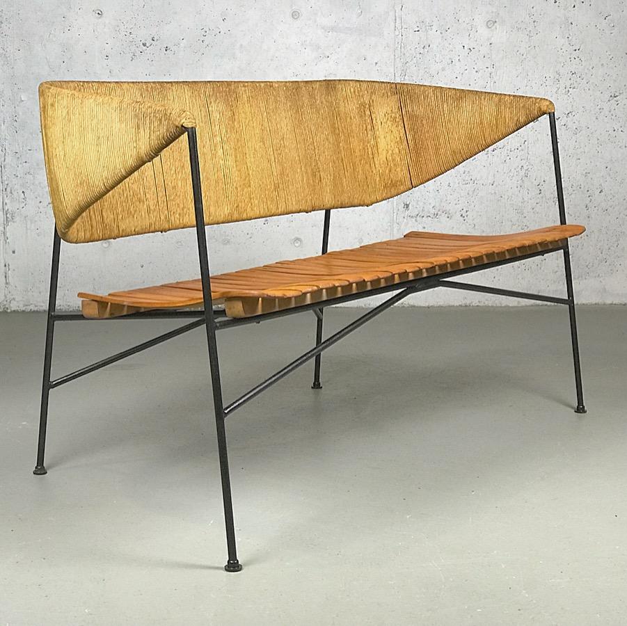 An exceptional example of American Modern design from the 1950s; Minimalist settee or bench designed by Arthur Umanoff for Shaver Howard. Made of iron, wood and papercord. Nice patina on the paper-cord and wood slats show slight wear. Nice vintage