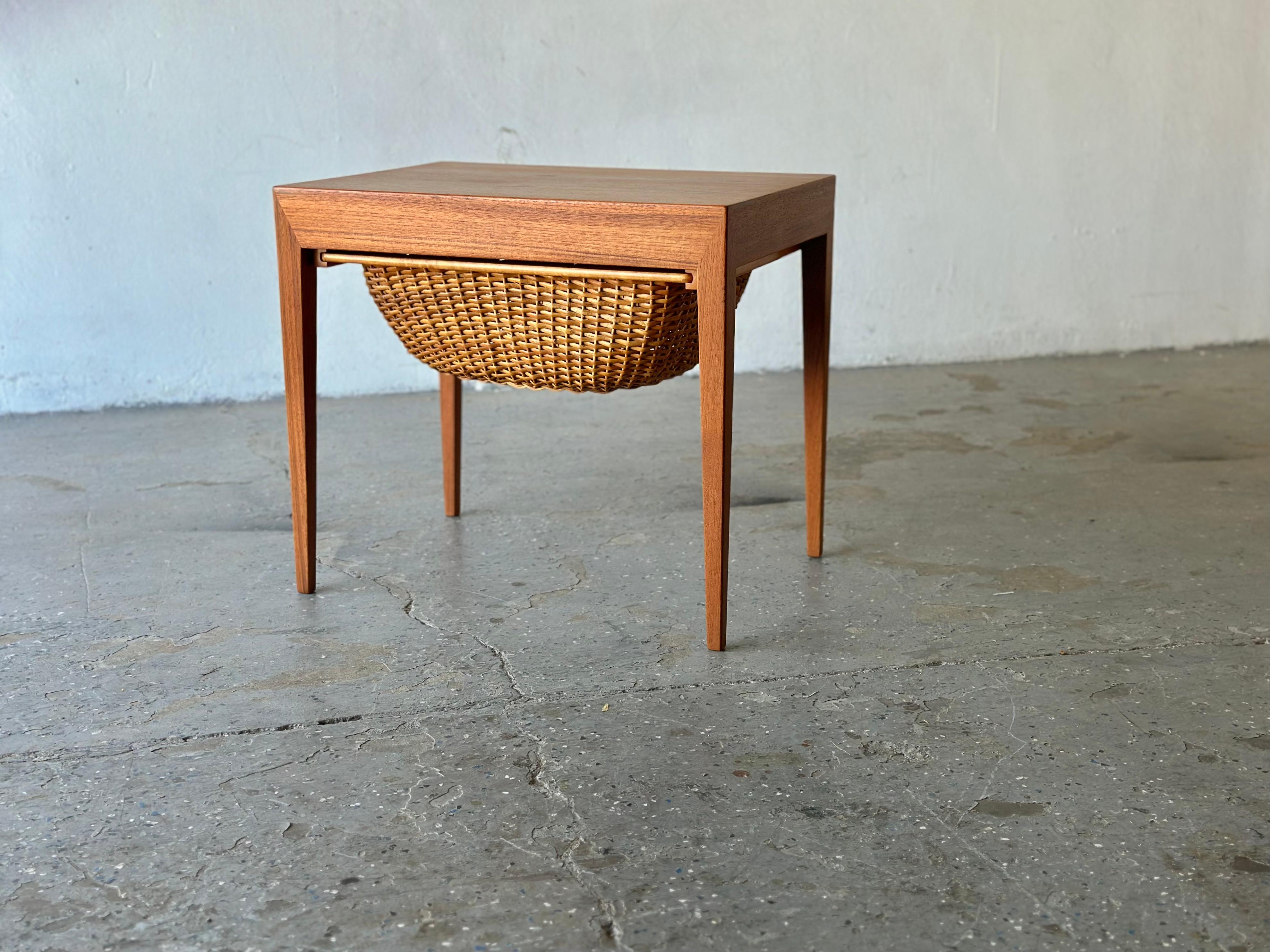 Sewing bedside /end / side table in teak designed by Severin Hansen. Produced by Haslev Møbelsnedkeri, Denmark. Very desirable table finished in teak with a rattan woven shelf beneath a single drawer. 

Gracious proportions and a fantastic